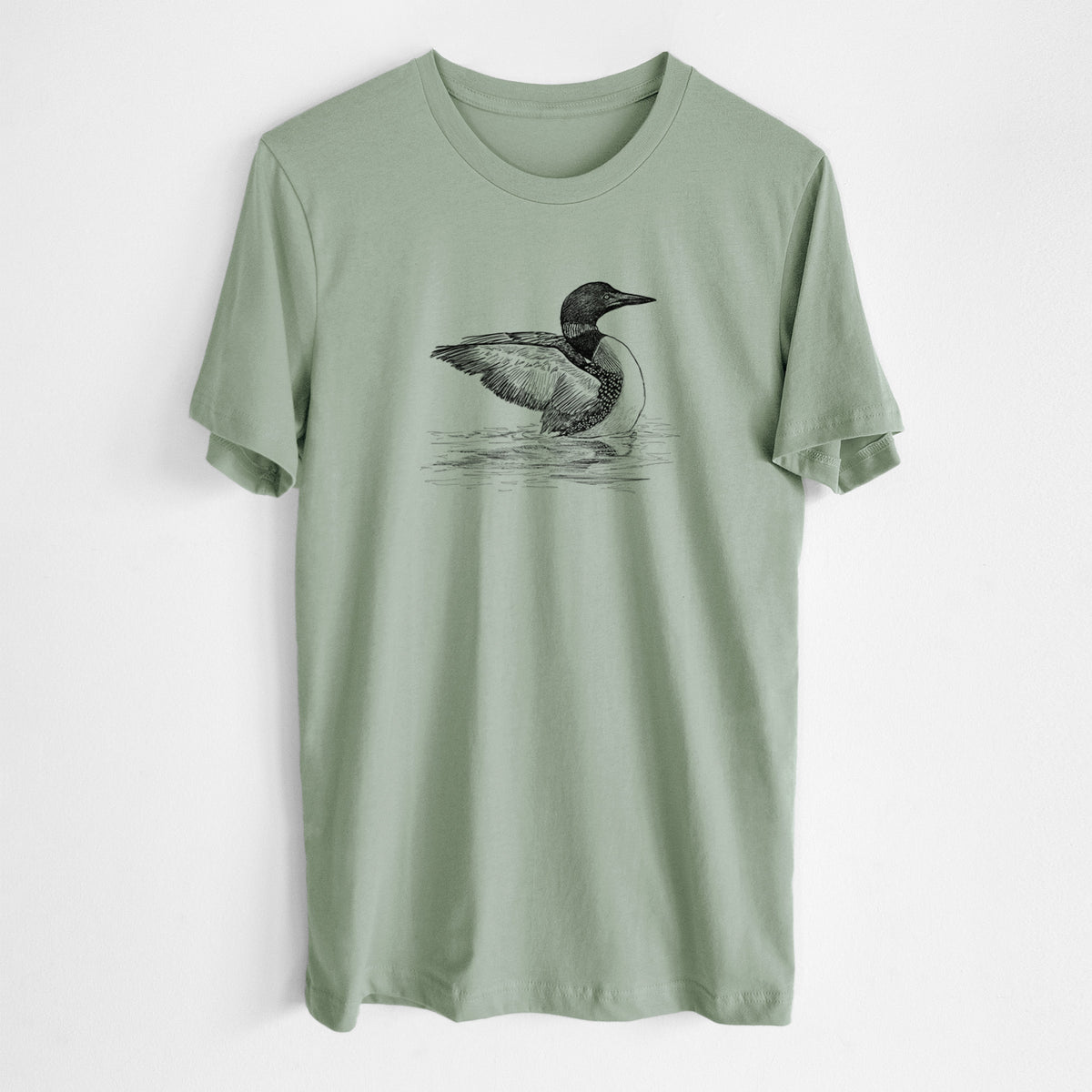Sage green lightweight cotton t-shirt laid flat, printed with a detailed black ink sketch of a common loon floating on rippling water.