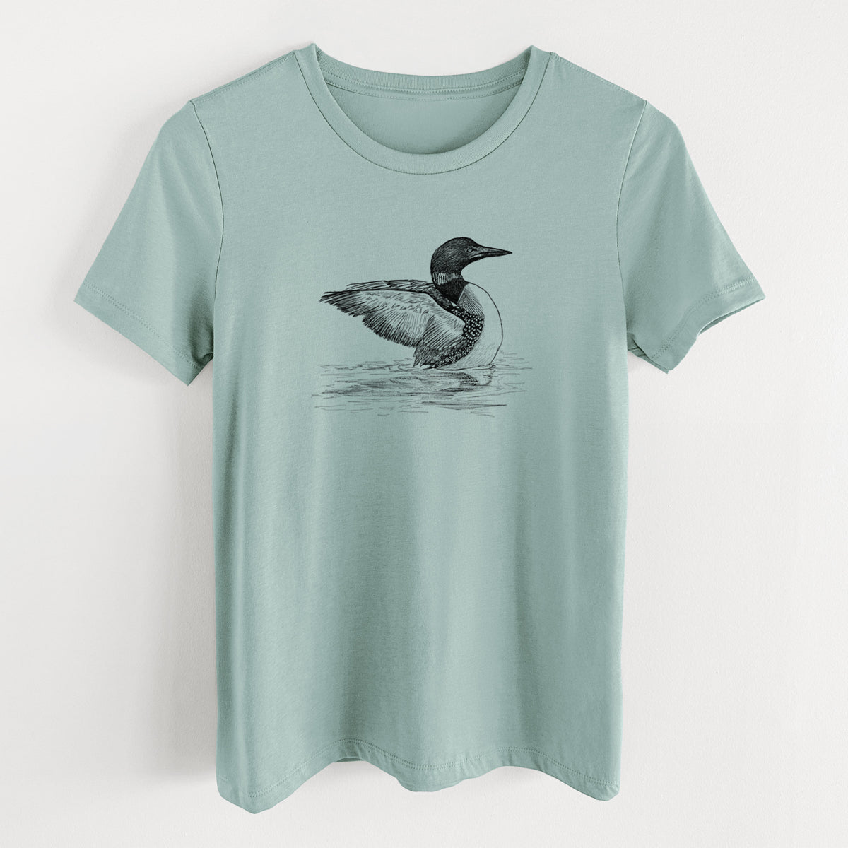 Dusty blue women's relaxed fit cotton t-shirt laid flat, printed with a detailed black ink sketch of a common loon floating on rippling water.