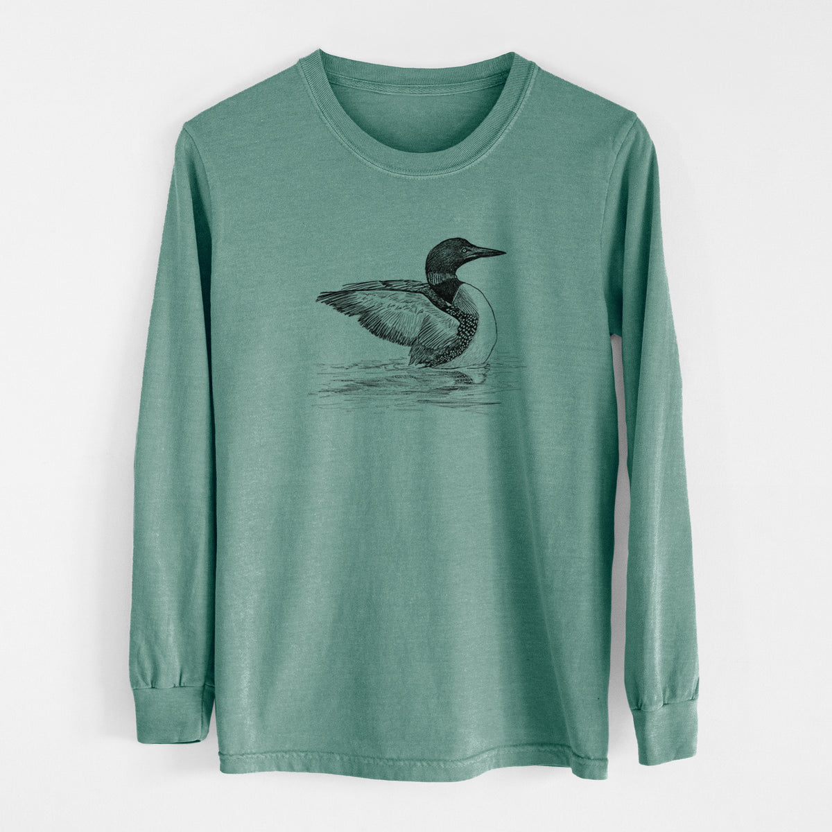 Pine green Comfort Colors long sleeve shirt laid flat, printed with a detailed black ink sketch of a common loon floating on rippling water.