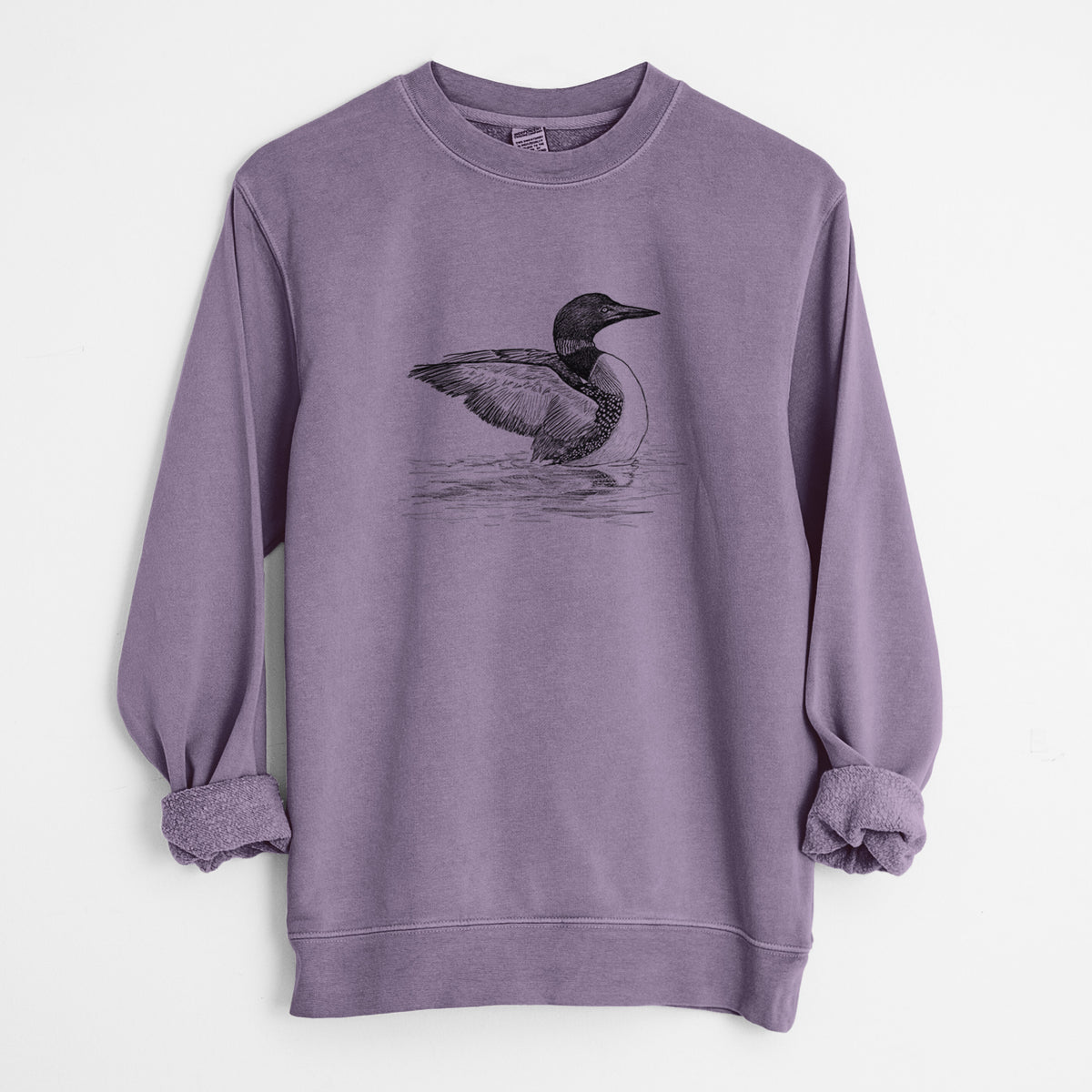 Plum purple pigment dyed crewneck sweatshirt laid flat with the sleeves rolled, printed with a detailed black ink sketch of a common loon floating on rippling water.