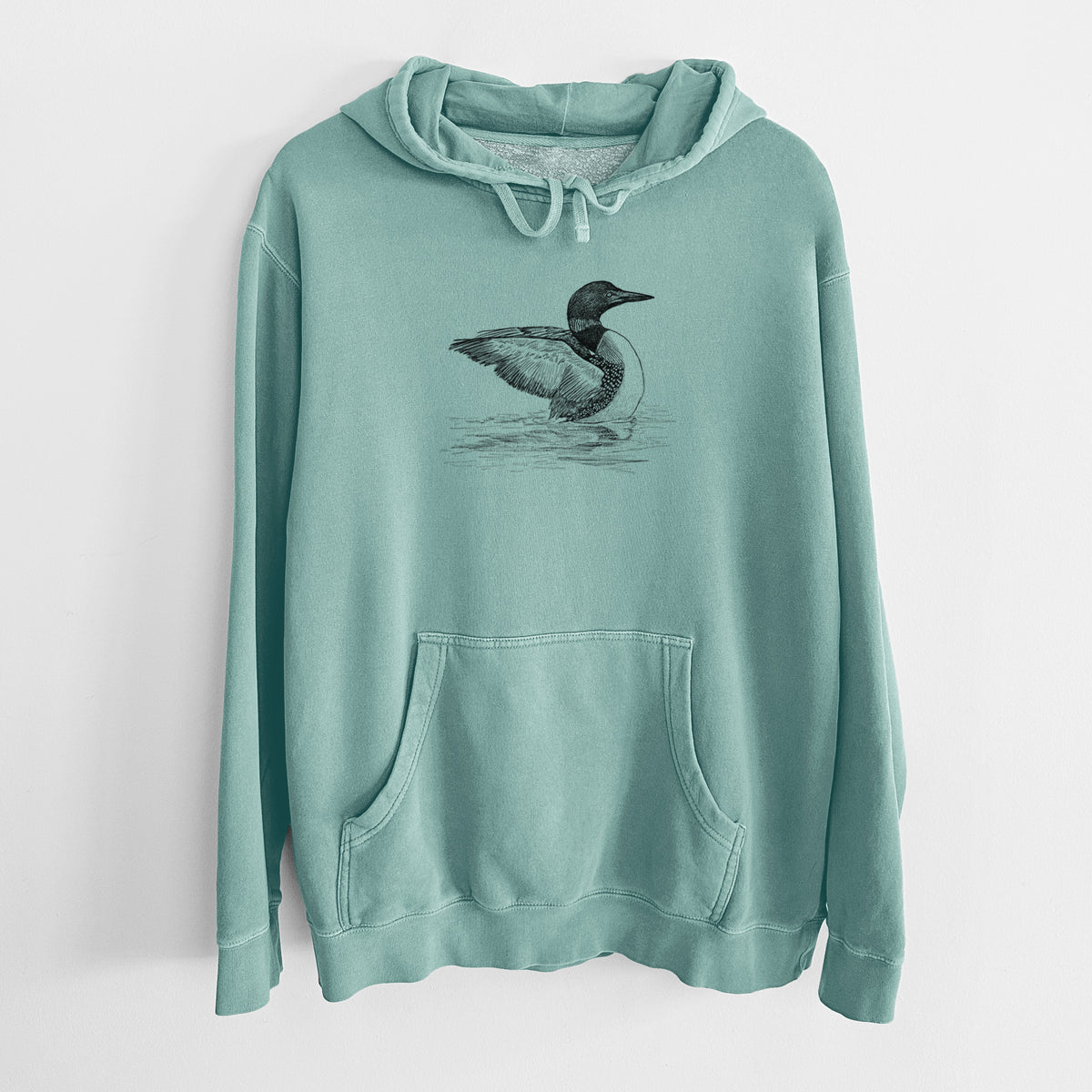 Mint green pigment dyed hoodie laid flat, printed with a detailed black ink sketch of a common loon floating on rippling water.