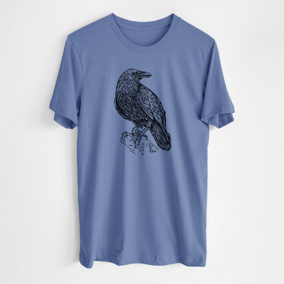 Blue bell lightweight cotton t-shirt laid flat, printed with a detailed black ink sketch of a common raven perched on a rock.