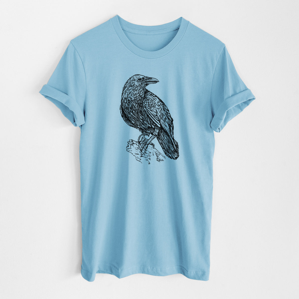 Ocean blue lightweight cotton t-shirt laid flat, printed with a detailed black ink sketch of a common raven perched on a rock.