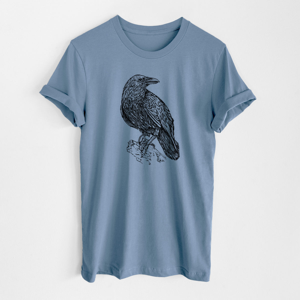 Steel blue lightweight cotton t-shirt laid flat, printed with a detailed black ink sketch of a common raven perched on a rock.