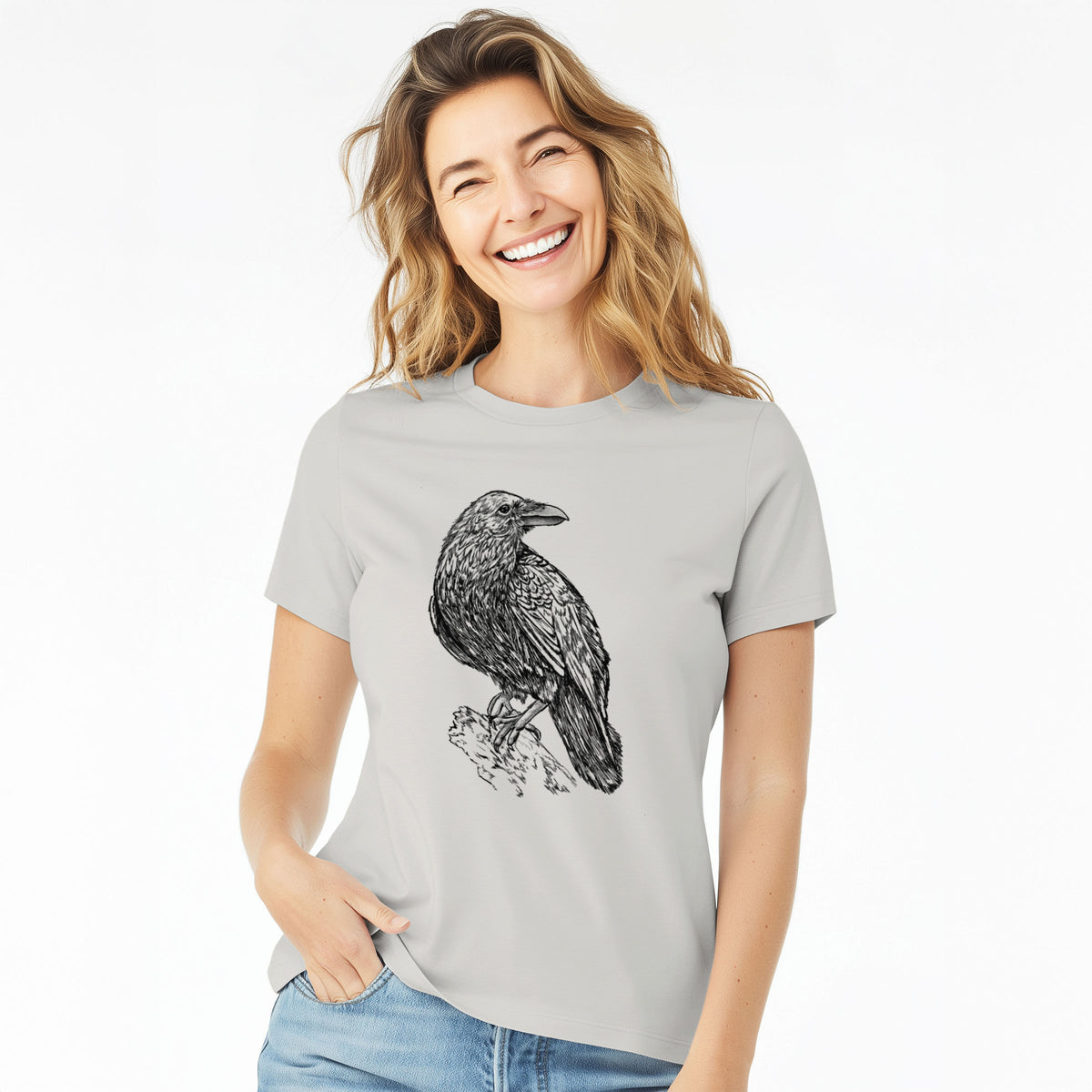 Woman wearing a lunar grey women's relaxed fit cotton t-shirt printed with a detailed black ink sketch of a common raven perched on a rock.
