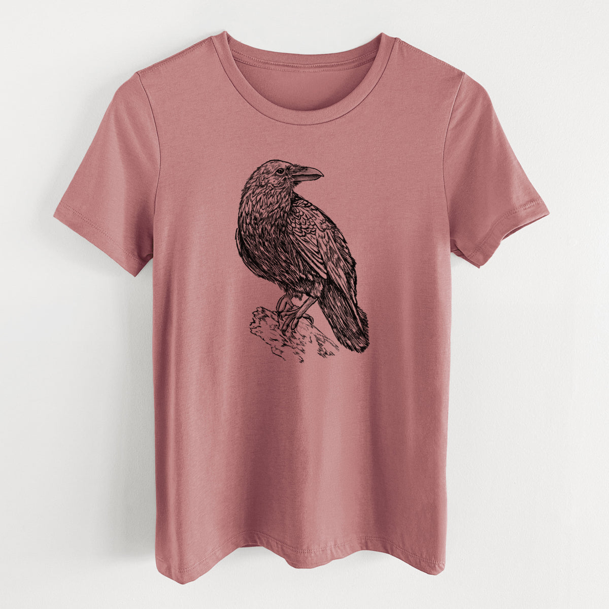 Mauve pink women's relaxed fit cotton t-shirt laid flat, printed with a detailed black ink sketch of a common raven perched on a rock.