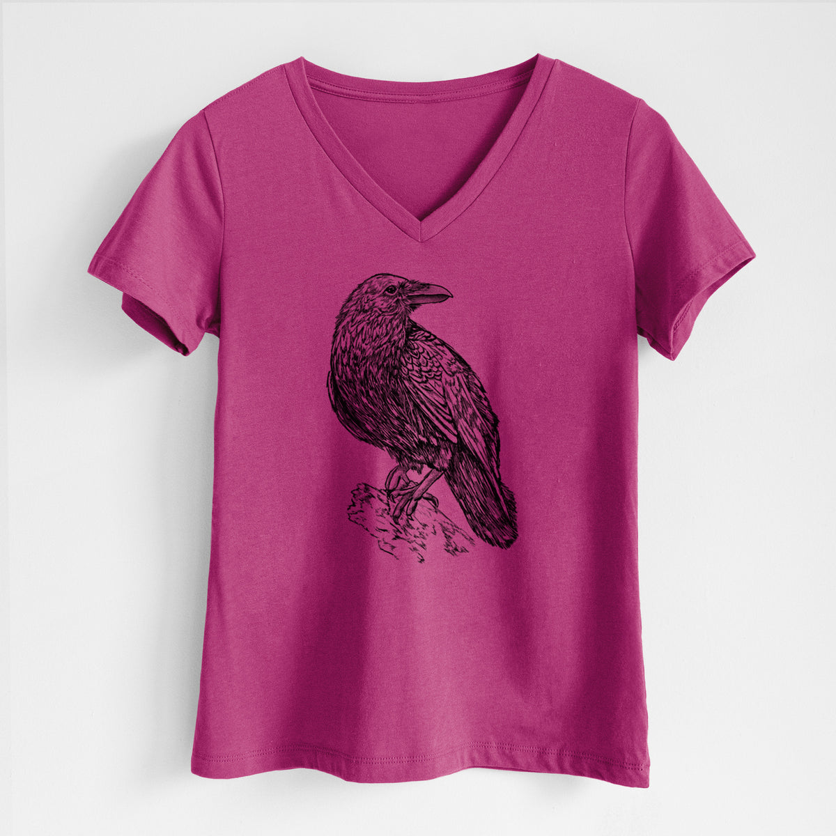 Berry pink women's relaxed fit cotton V-neck t-shirt laid flat, printed with a detailed black ink sketch of a common raven perched on a rock.