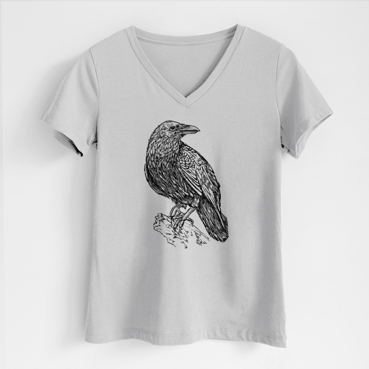 Lunar grey women's relaxed fit cotton V-neck t-shirt laid flat, printed with a detailed black ink sketch of a common raven perched on a rock.