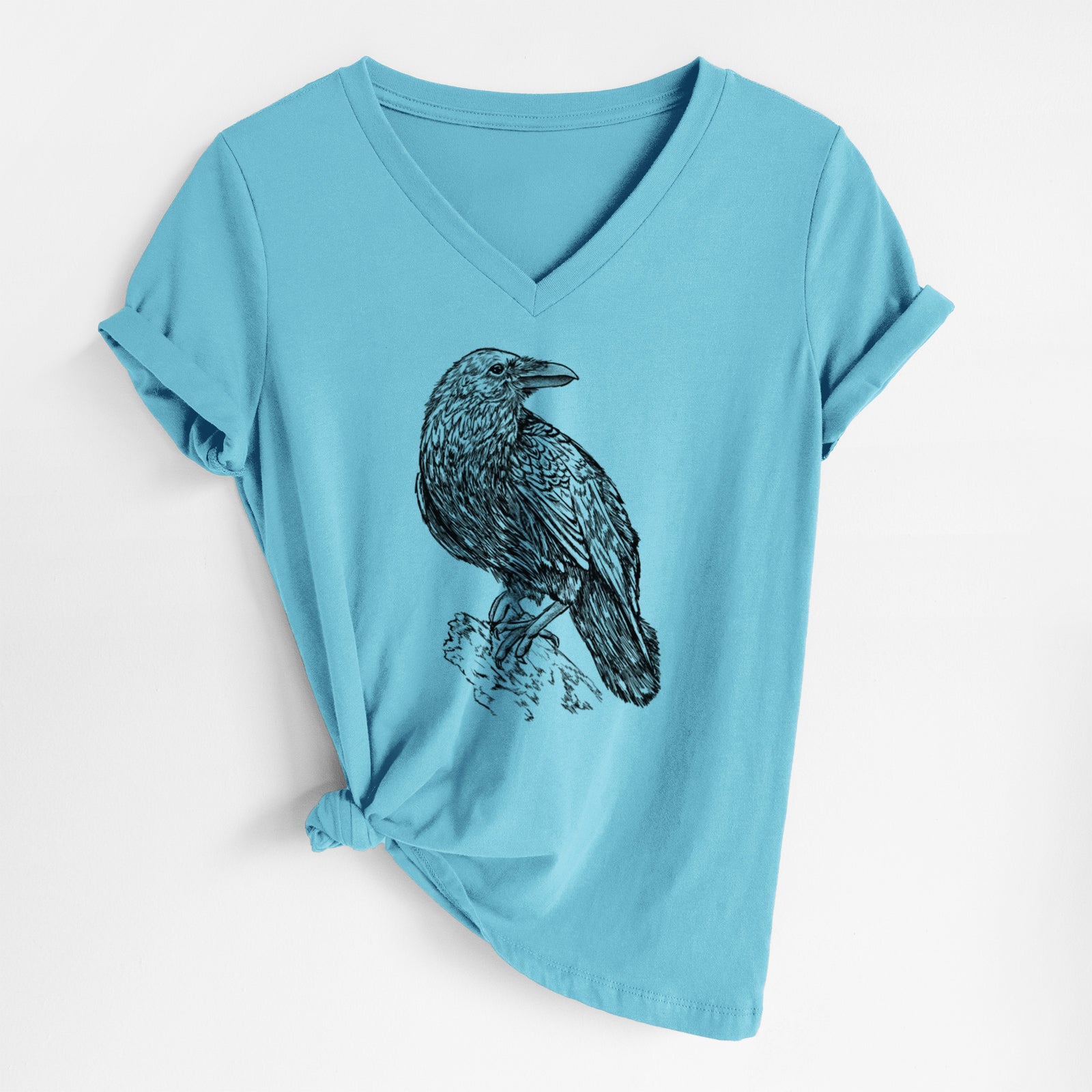 Turquoise women's relaxed fit cotton V-neck t-shirt laid flat, printed with a detailed black ink sketch of a common raven perched on a rock.