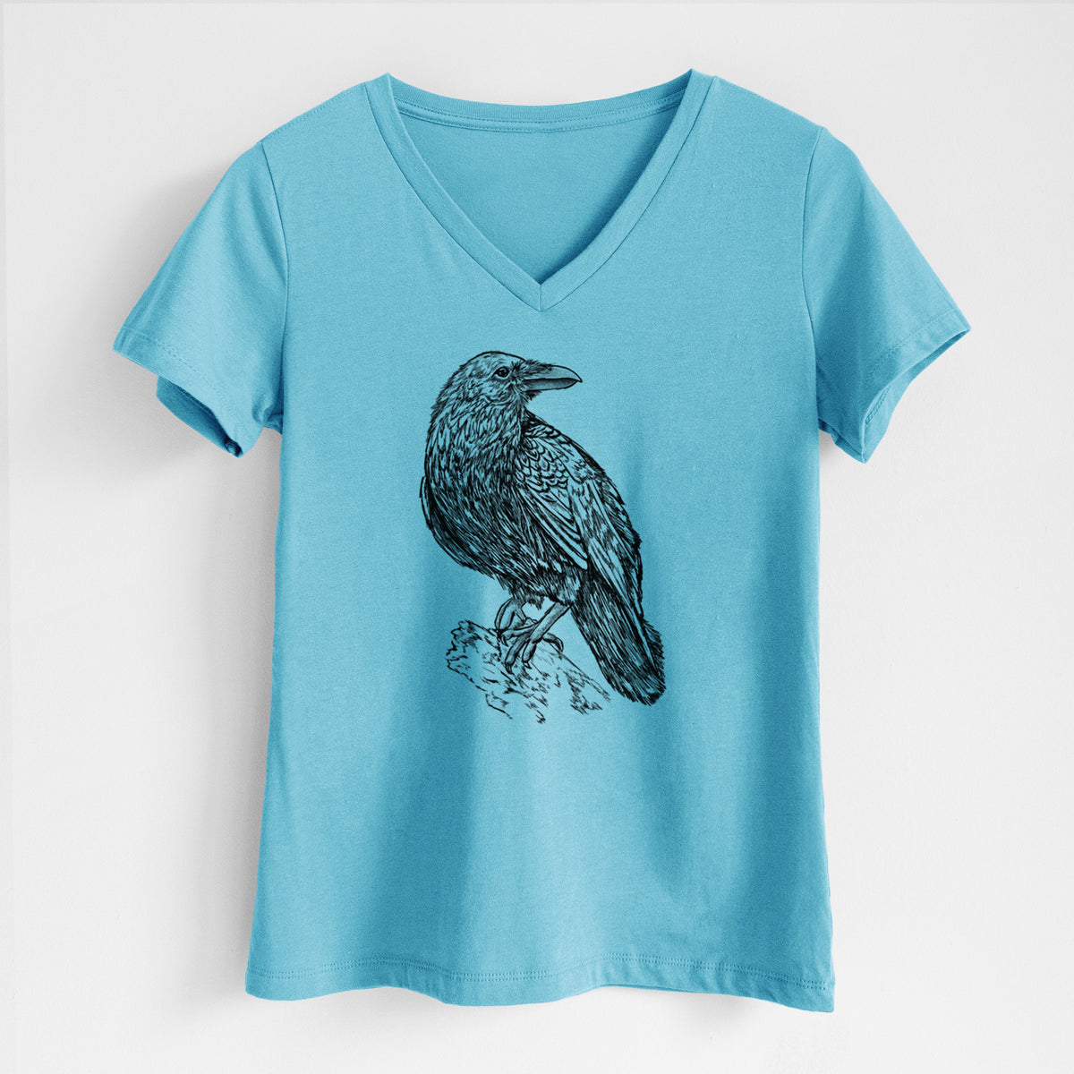 Turquoise women's relaxed fit cotton V-neck t-shirt laid flat, printed with a detailed black ink sketch of a common raven perched on a rock.