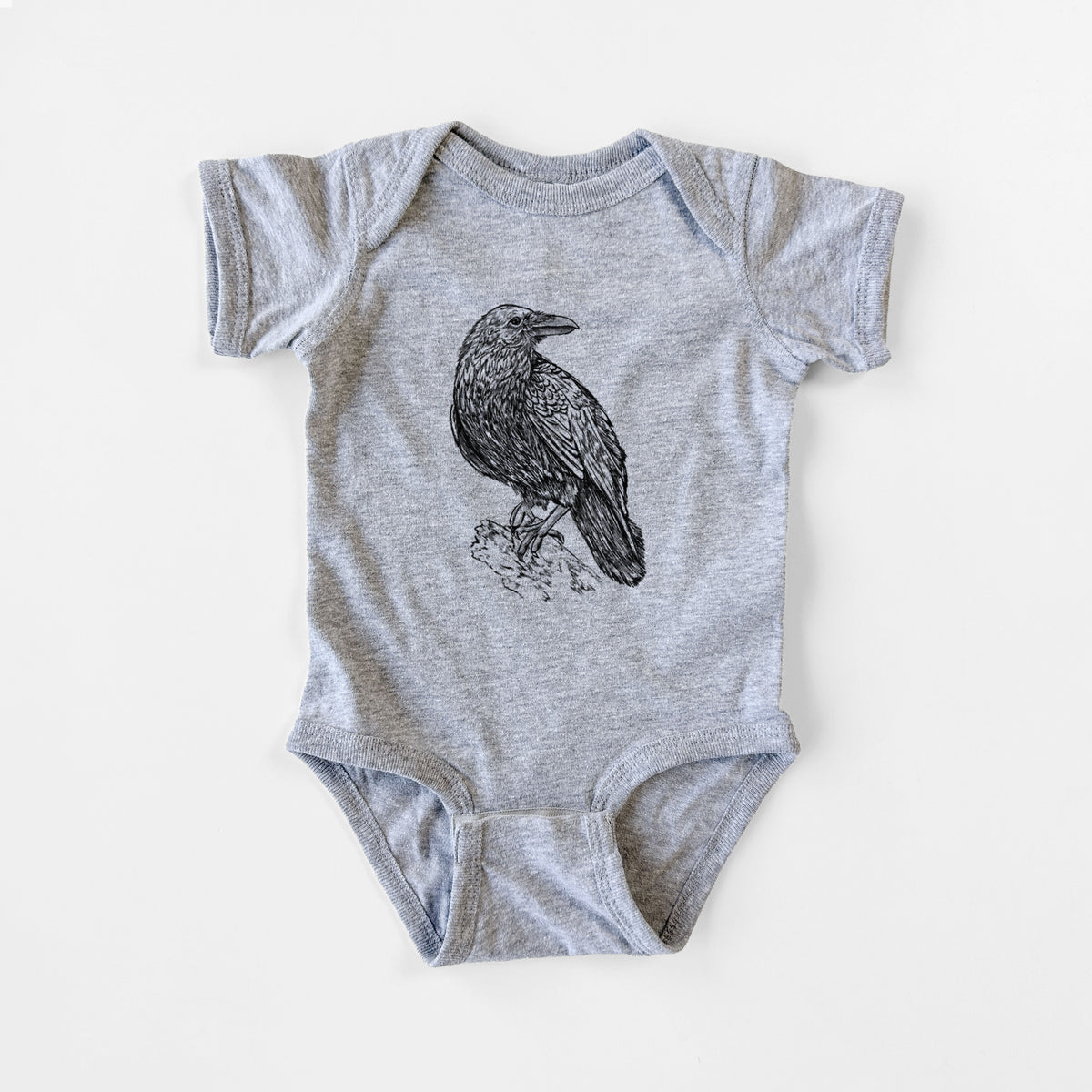 Grey baby bodysuit laid flat, printed with a detailed black ink sketch of a common raven perched on a rock.