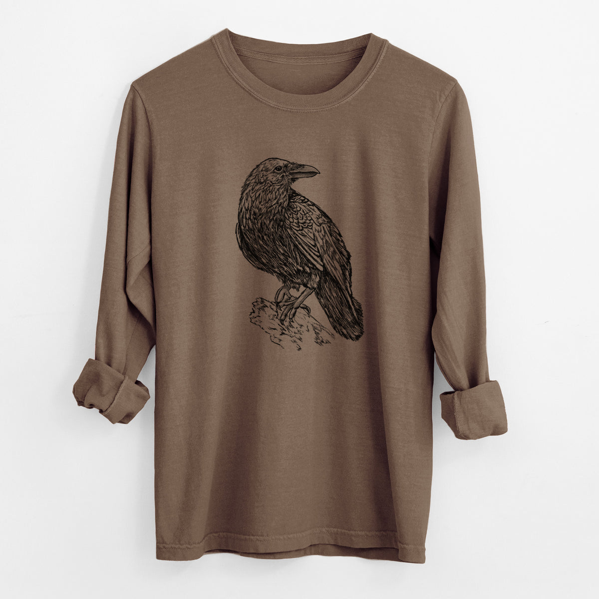 Espresso brown Comfort Colors long sleeve shirt laid flat with the cuffs rolled, printed with a detailed black ink sketch of a common raven perched on a rock.