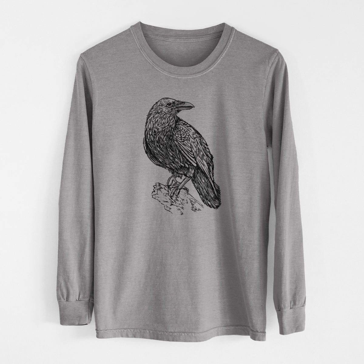 Grey Comfort Colors long sleeve shirt laid flat, printed with a detailed black ink sketch of a common raven perched on a rock.