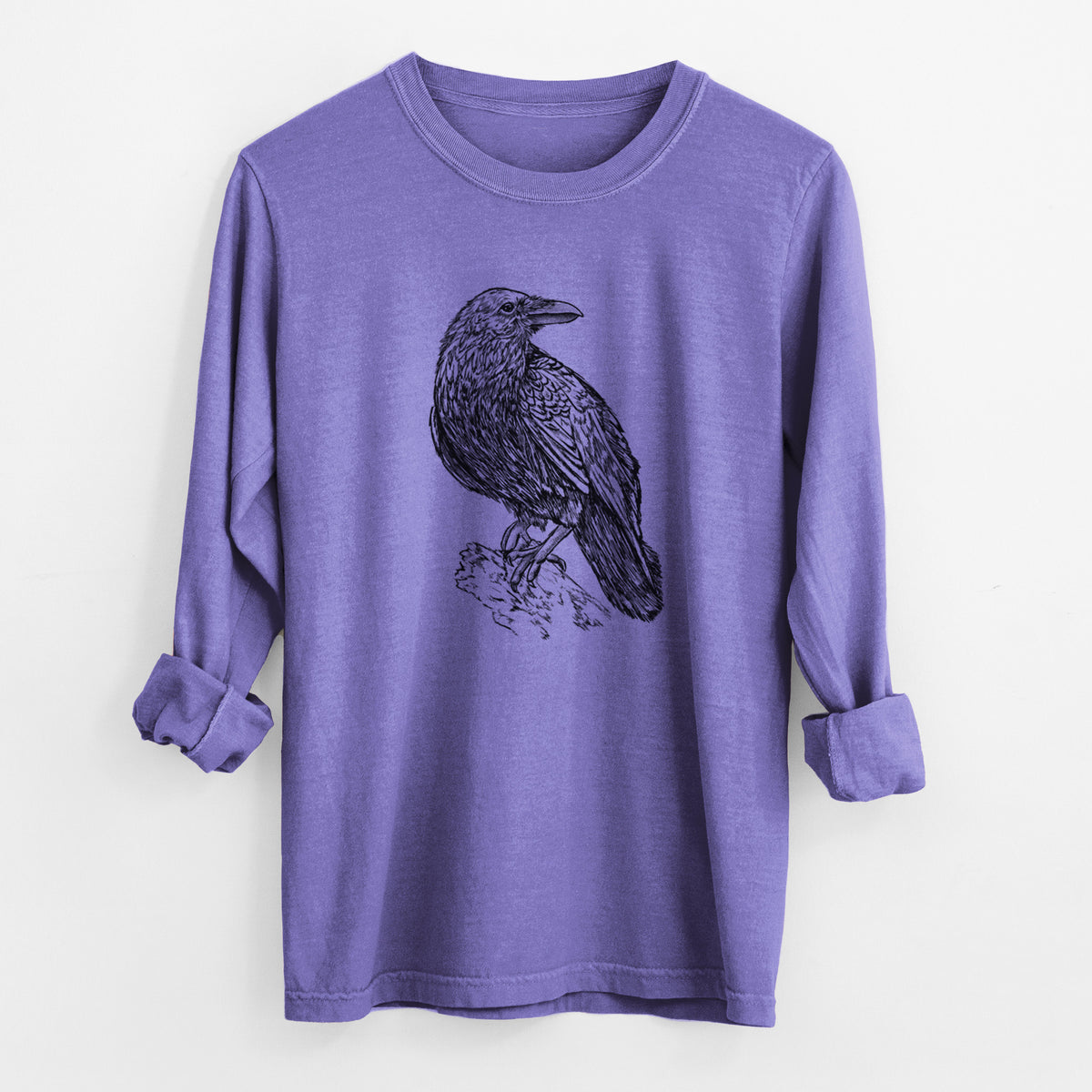 Violet purple Comfort Colors long sleeve shirt laid flat with the cuffs rolled, printed with a detailed black ink sketch of a common raven perched on a rock.