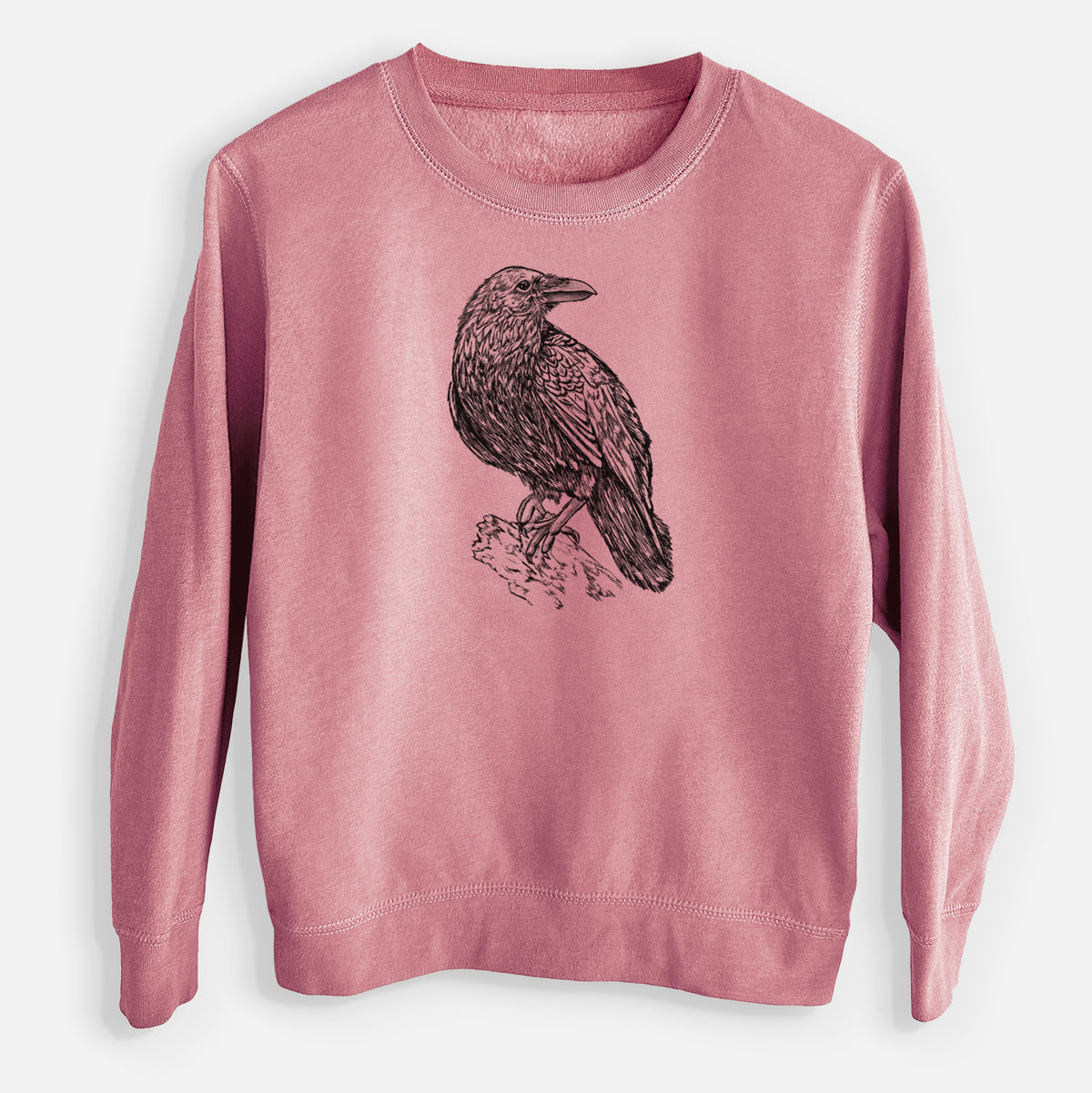 Mauve pink youth crewneck sweatshirt laid flat, printed with a detailed black ink sketch of a common raven perched on a rock.