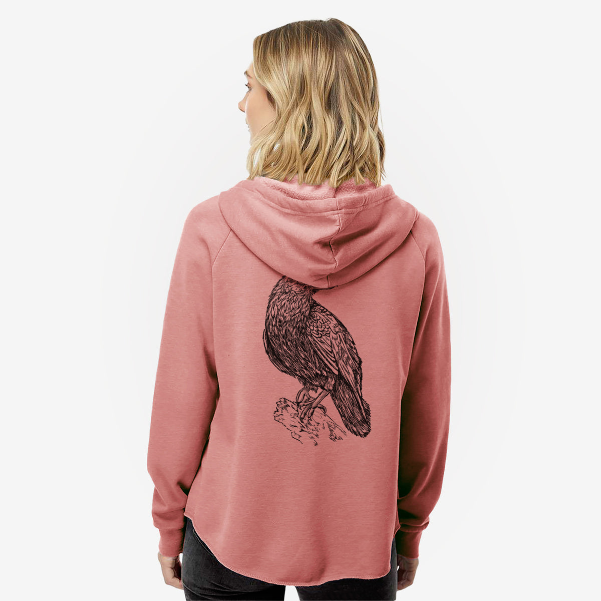Woman wearing a dusty rose women's Cali Wave zip-up sweatshirt printed with a detailed black ink sketch of a common raven perched on a rock, seen from behind.
