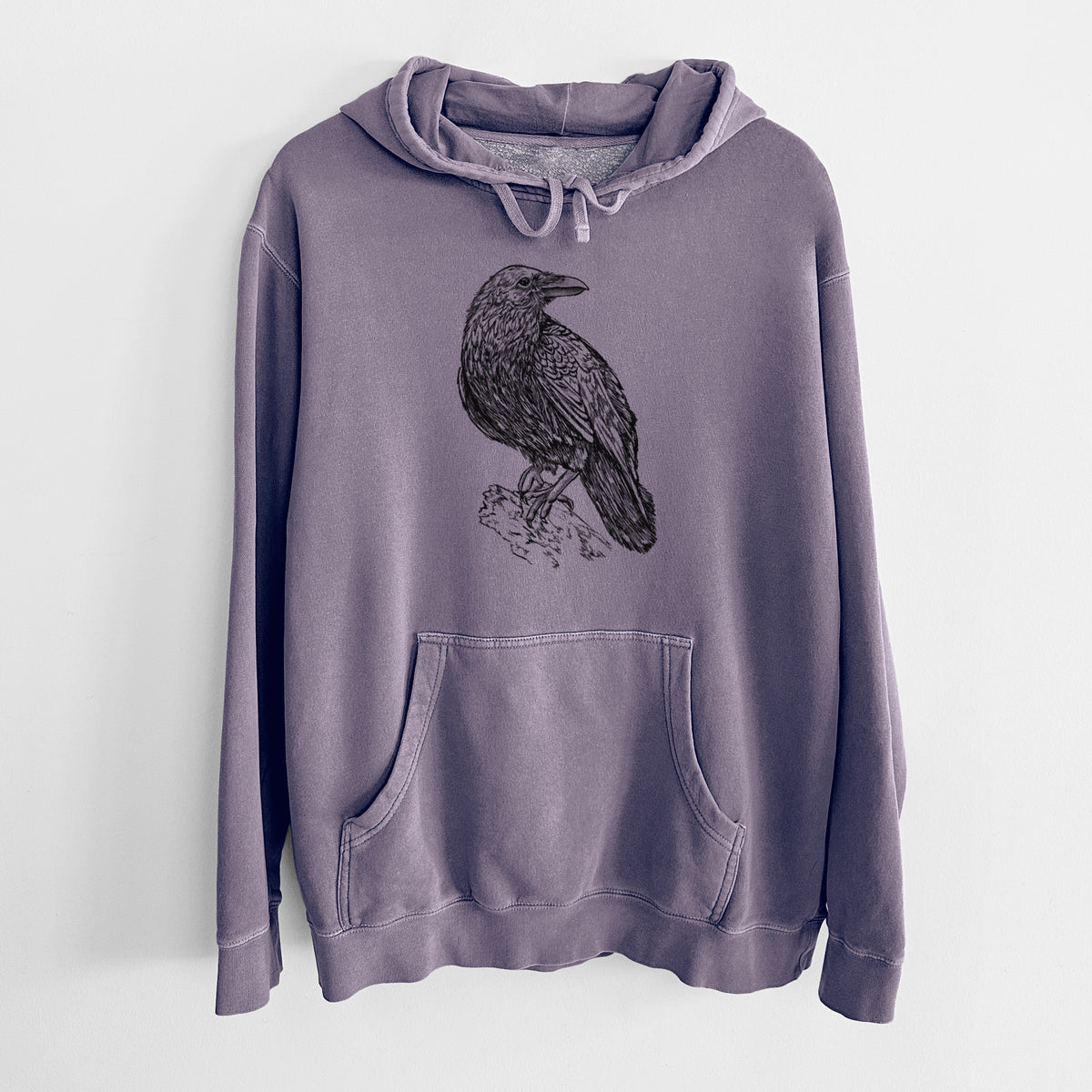 Plum purple pigment dyed hoodie laid flat, printed with a detailed black ink sketch of a common raven perched on a rock.