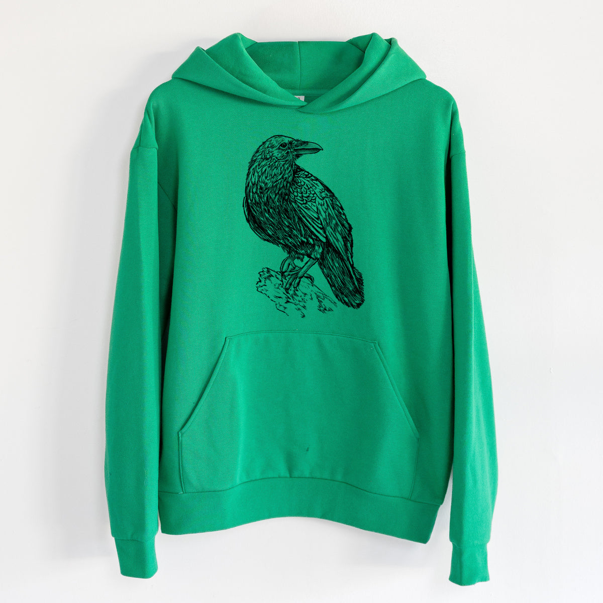 Corvus corax - Common Raven - Statement Midweight Hoodie in Kelly Green, hanging on a white wall, with a front kangaroo pocket and no drawcords.