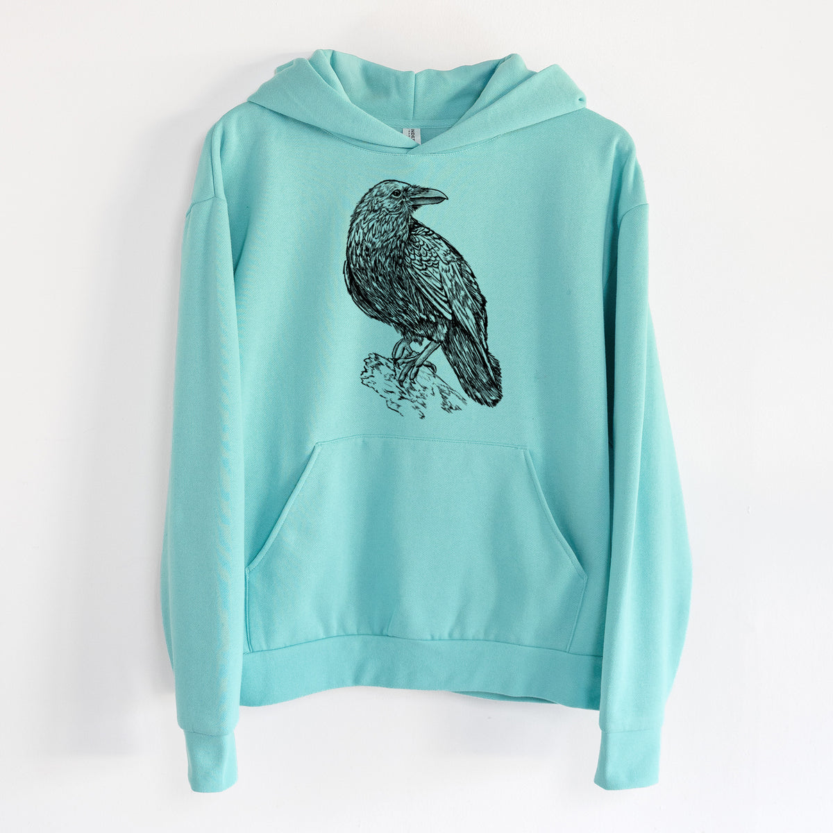 Corvus corax - Common Raven - Statement Midweight Hoodie in Seafoam, hanging on a white wall, with a front kangaroo pocket and no drawcords.
