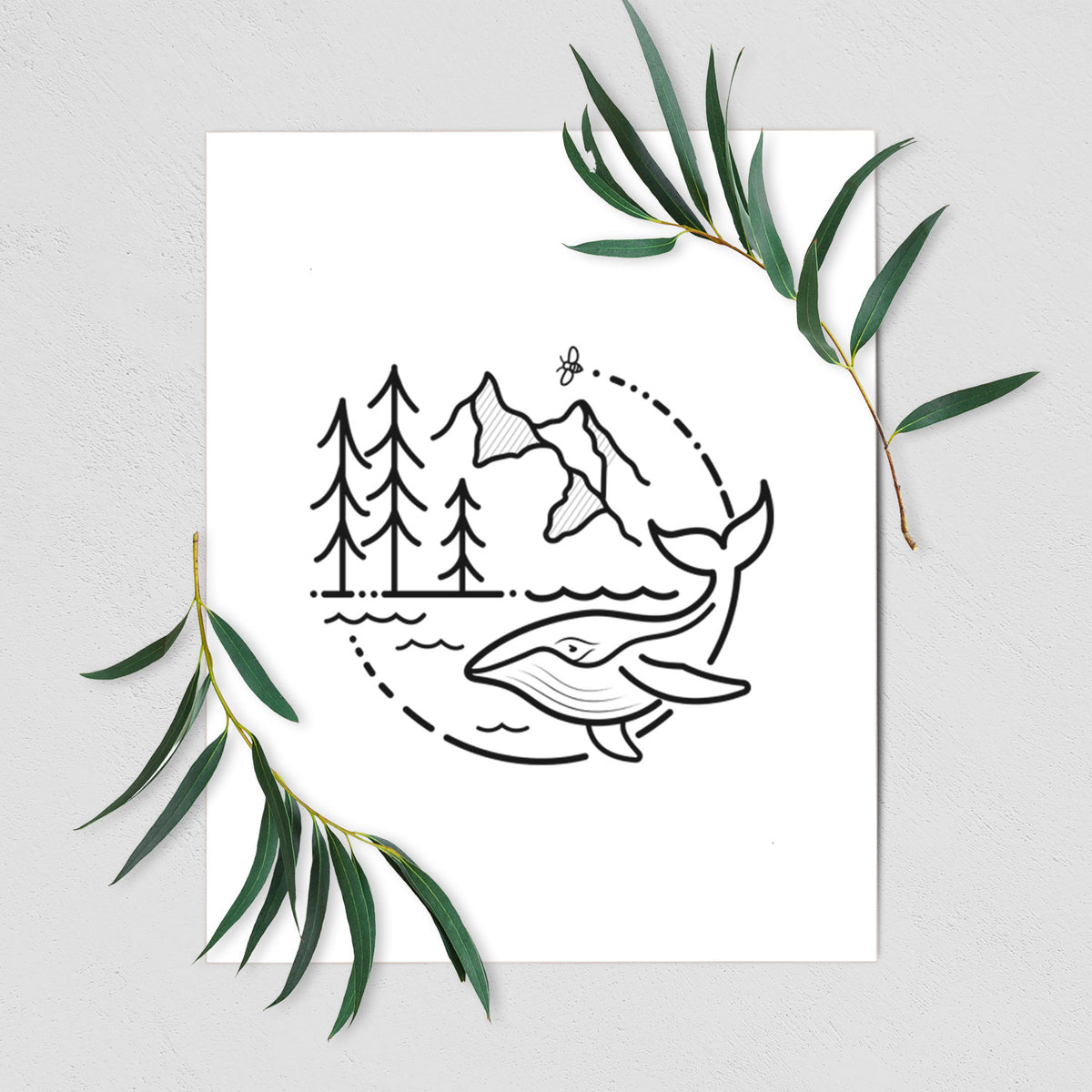 Art print of a black line art circle connecting a mountain range, pine trees, a bee and a whale swimming in ocean waves, shown with eucalyptus leaves.