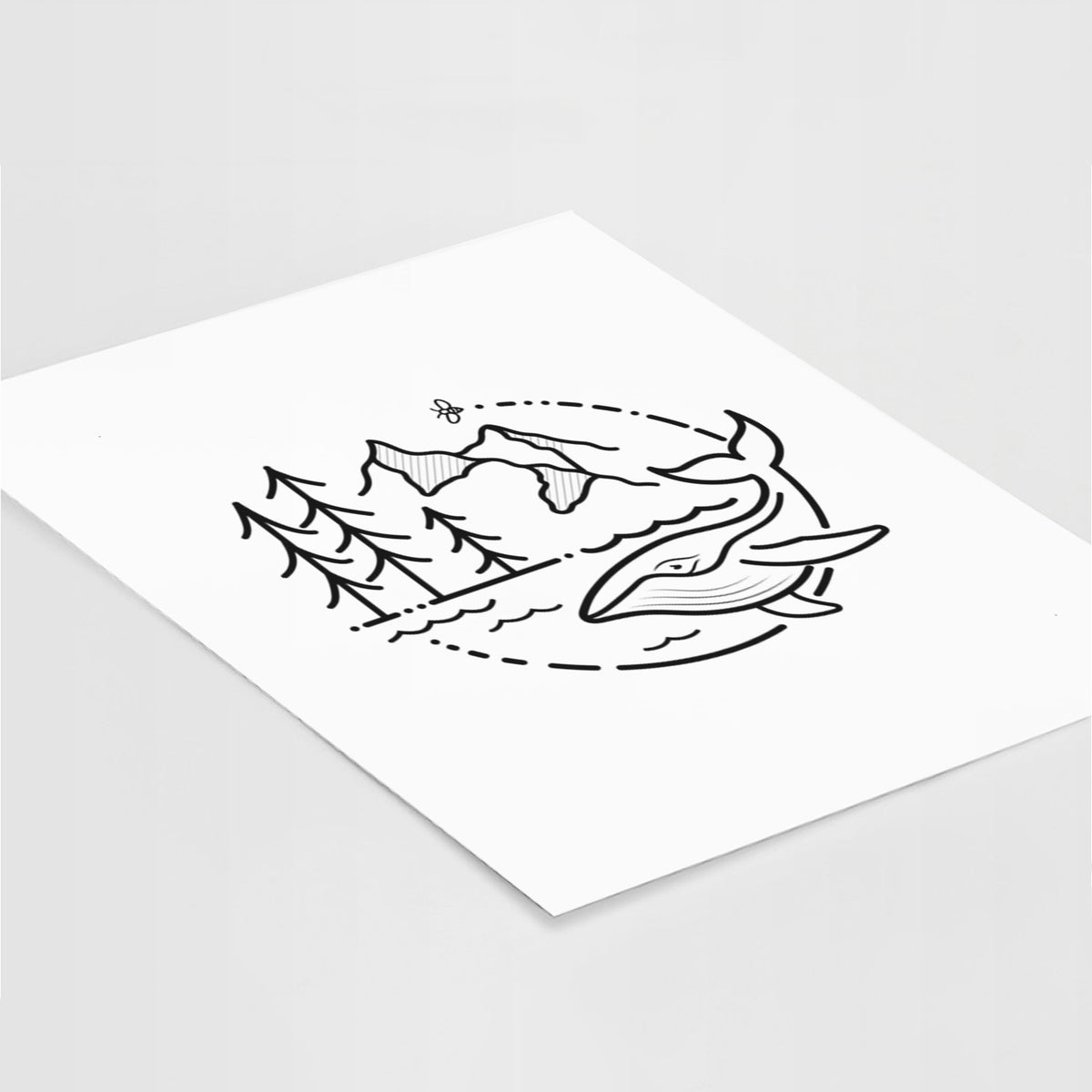 Art print of a black line art circle connecting a mountain range, pine trees, a bee and a whale swimming in ocean waves, lying at an angle on a white surface.