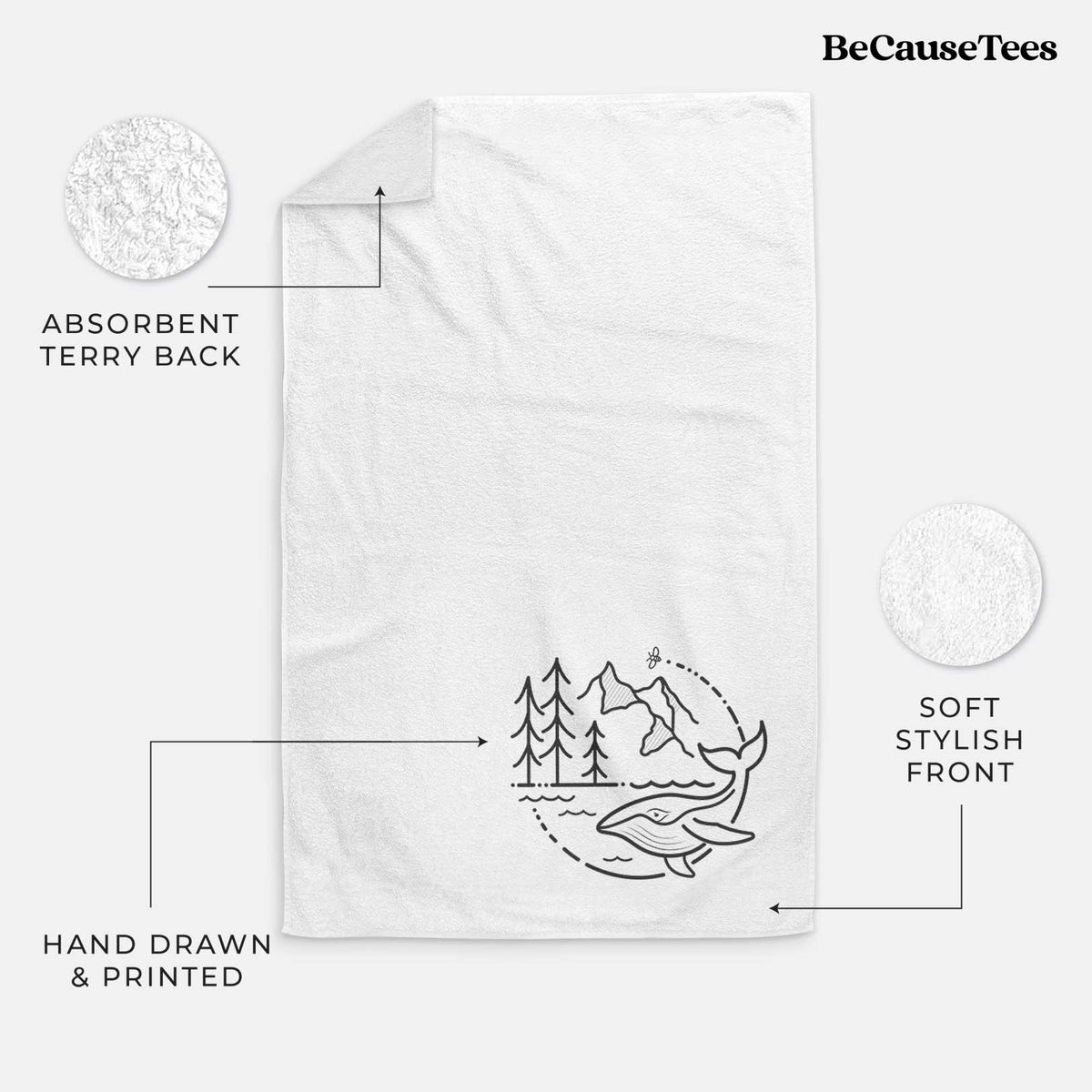 White hand towel printed with a black line art circle connecting a mountain range, pine trees, a bee and a whale swimming in ocean waves.
