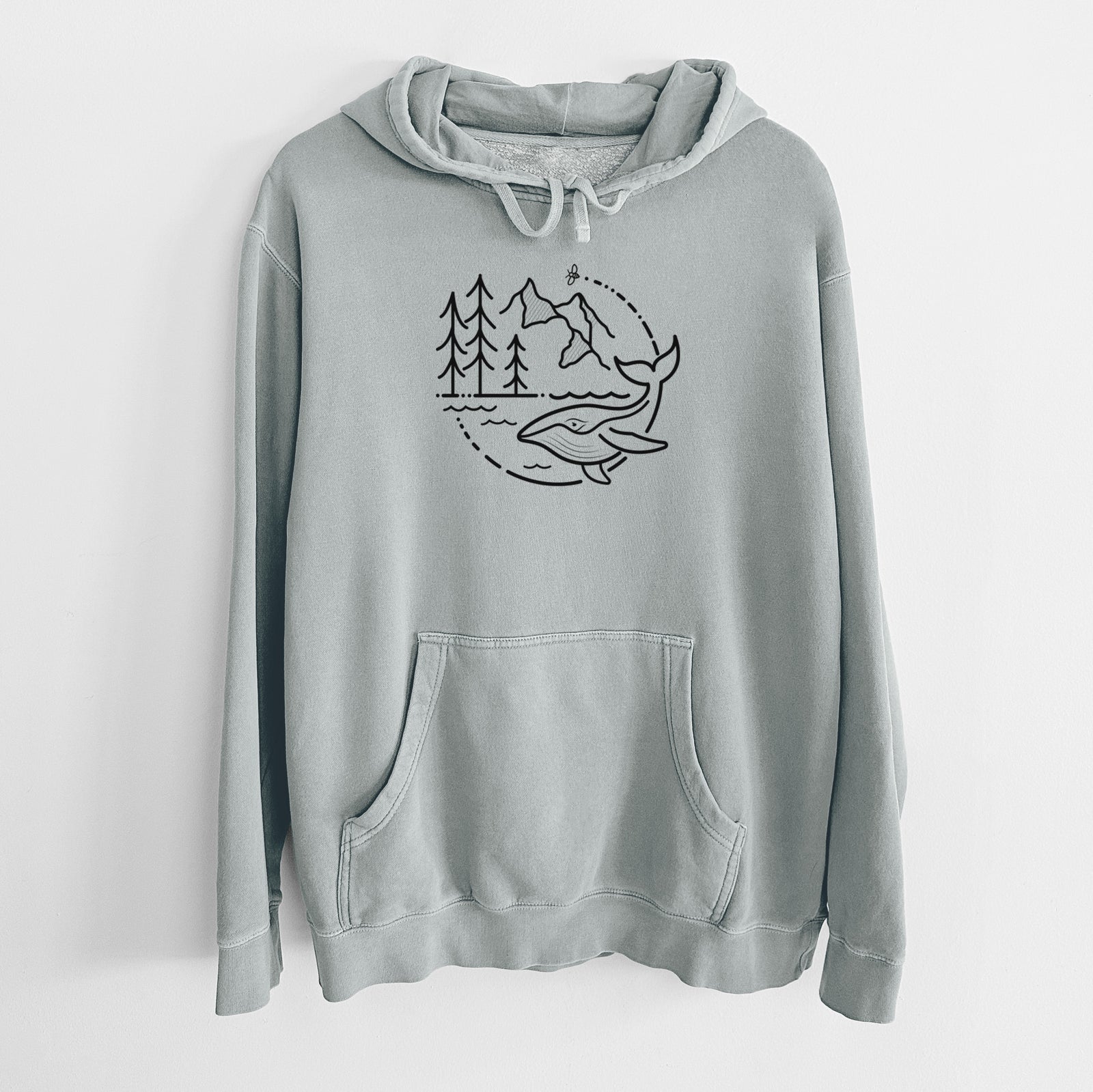 Sage green pigment dyed hoodie laid flat, printed with a black line art circle connecting a mountain range, pine trees, a bee and a whale swimming in ocean waves.