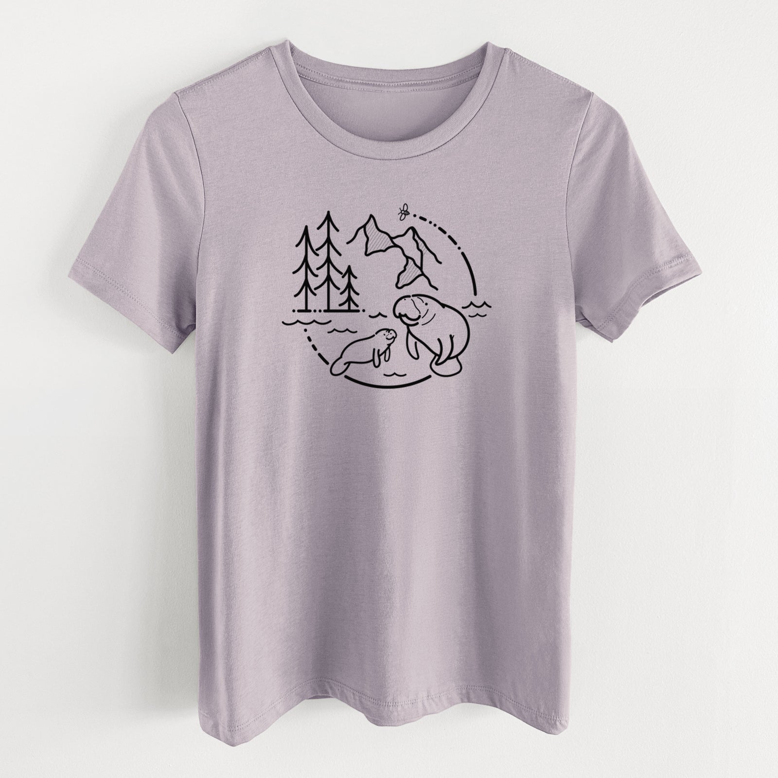 Light violet women's relaxed fit cotton t-shirt laid flat, printed with a black line art circle connecting pine trees, mountains, a bee and two manatees swimming in water.