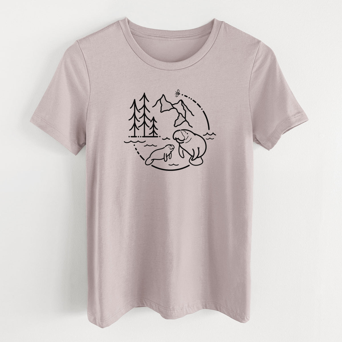 Pink gravel women's relaxed fit cotton t-shirt laid flat, printed with a black line art circle connecting pine trees, mountains, a bee and two manatees swimming in water.