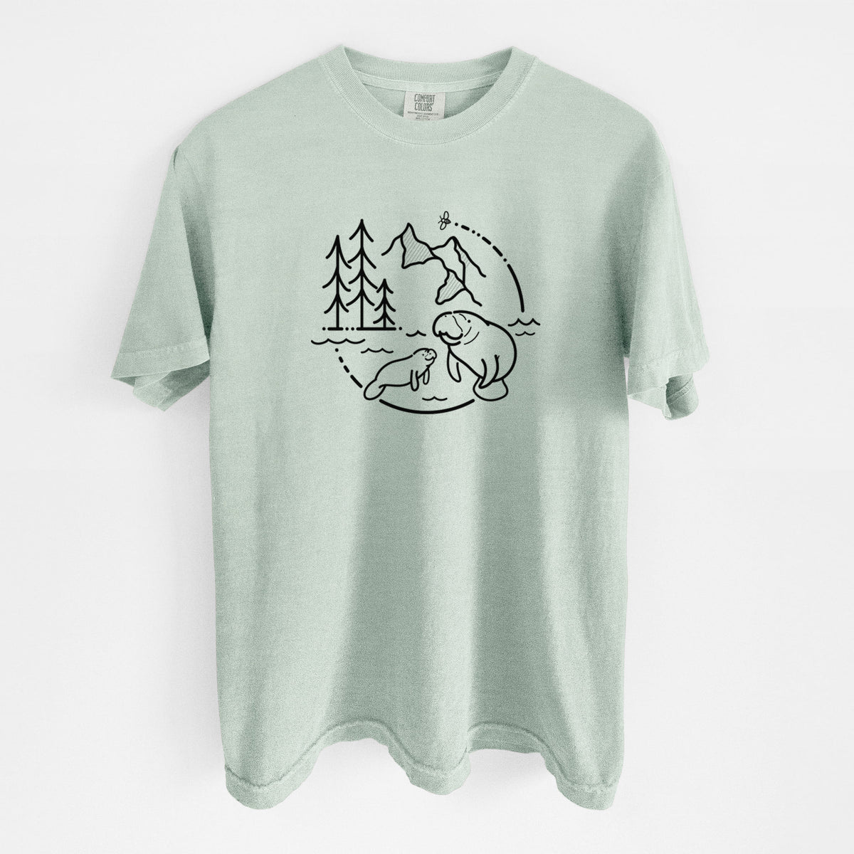 Bay green Comfort Colors t-shirt laid flat, printed with a black line art circle connecting pine trees, mountains, a bee and two manatees swimming in water.