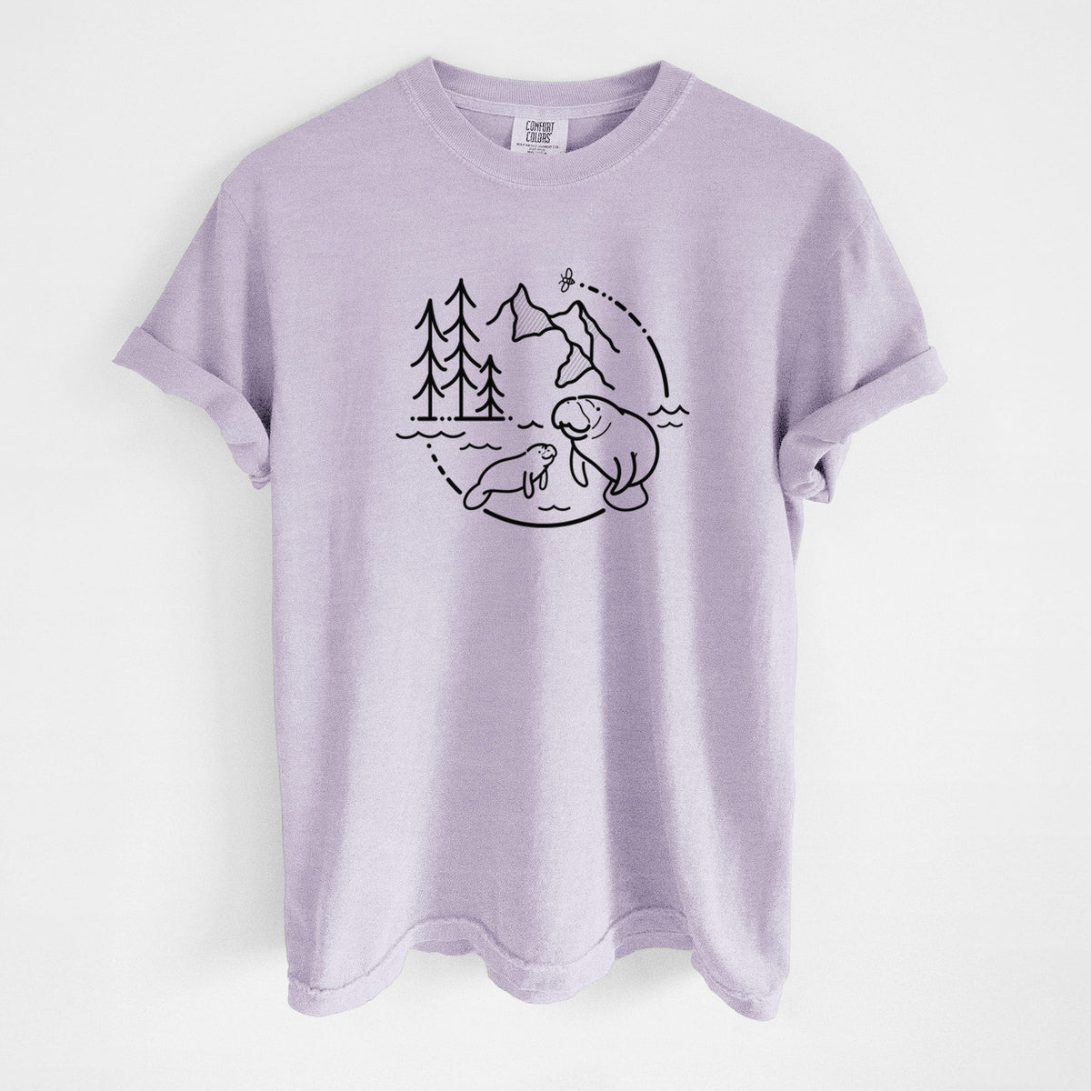 Orchid purple Comfort Colors t-shirt laid flat, printed with a black line art circle connecting pine trees, mountains, a bee and two manatees swimming in water.