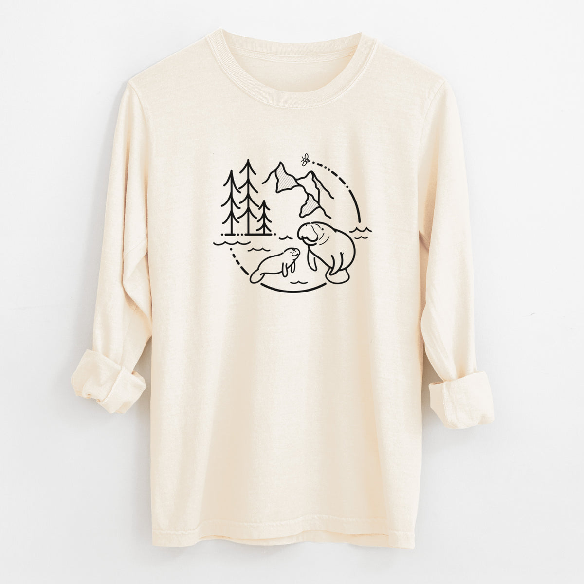 Ivory Comfort Colors long sleeve shirt laid flat with the cuffs rolled, printed with a black line art circle connecting pine trees, mountains, a bee and two manatees swimming in water.