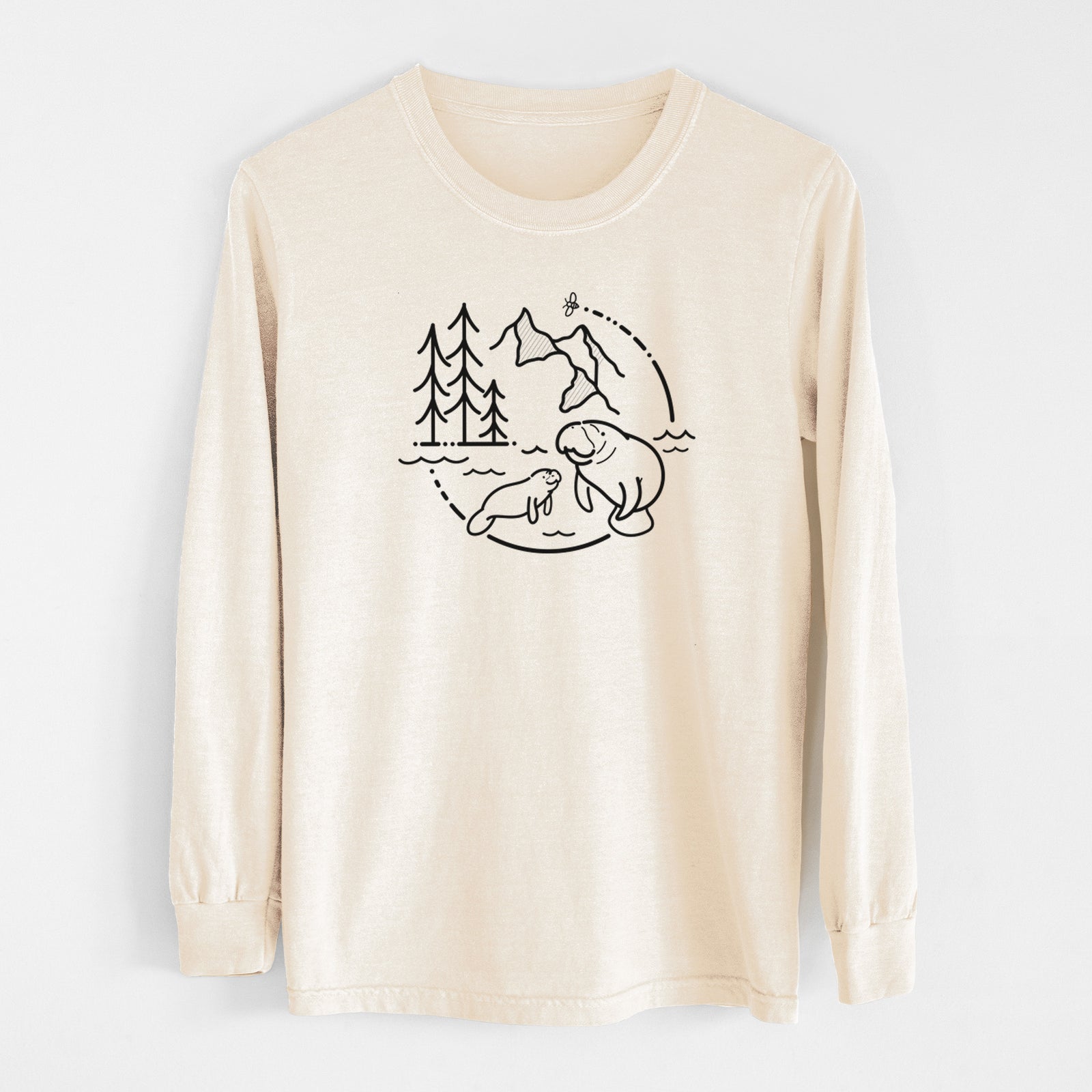 Ivory Comfort Colors long sleeve shirt laid flat, printed with a black line art circle connecting pine trees, mountains, a bee and two manatees swimming in water.