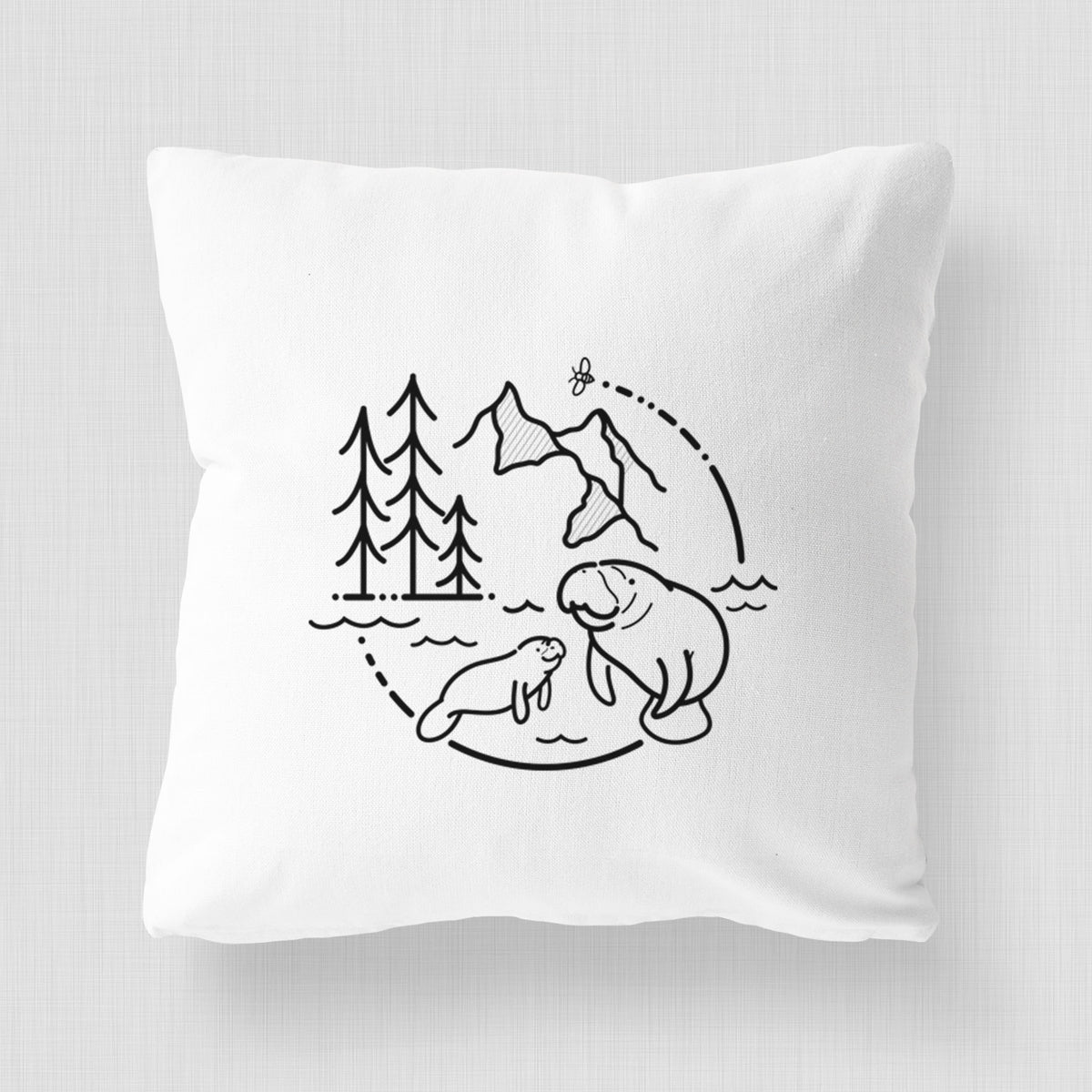 White pillow cover printed with a black line art circle connecting pine trees, mountains, a bee and two manatees swimming in water.