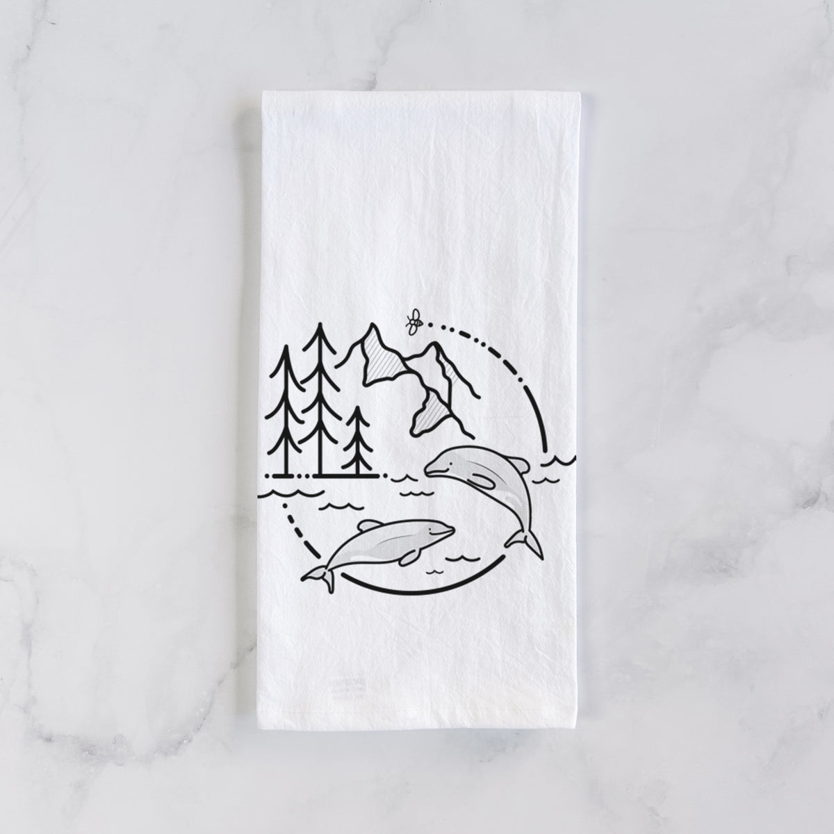 White cotton tea towel laid flat on marble, printed with a black line art circle connecting pine trees, mountains, a bee and two Maui dolphins leaping from the waves.