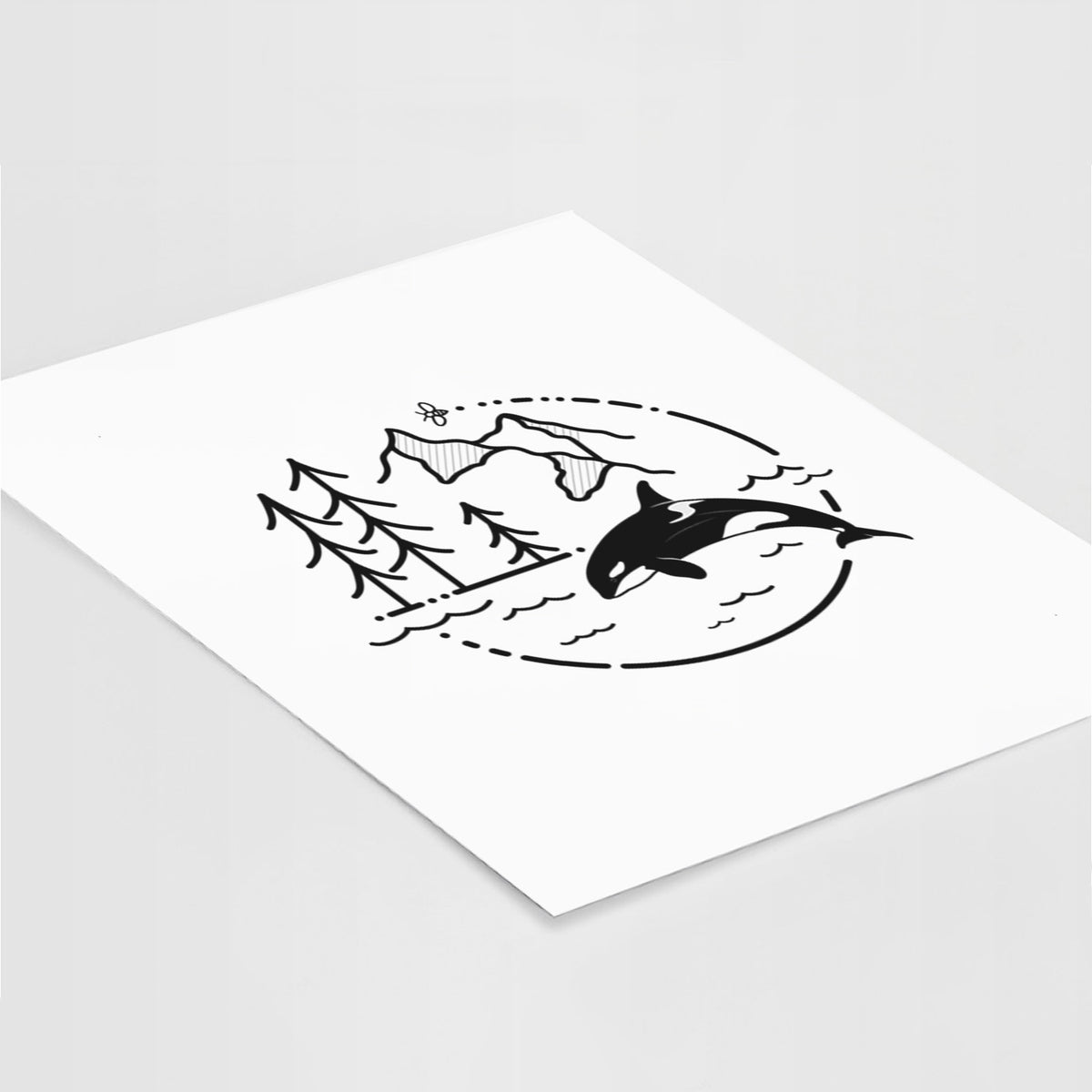 Art print of a black line art circle connecting pine trees, mountains, a bee and an orca leaping from ocean waves, lying at an angle on a white surface.
