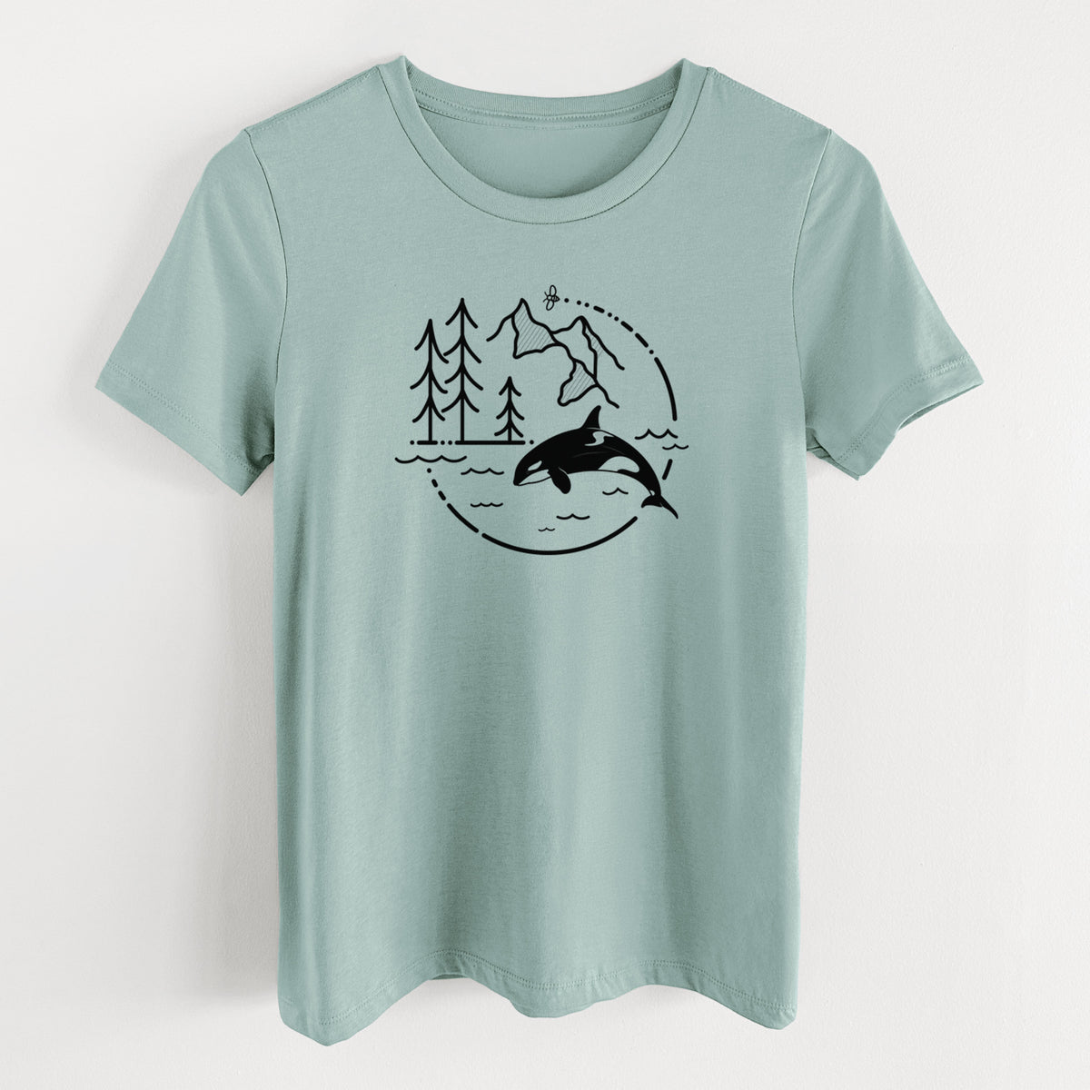 Dusty blue women's relaxed fit cotton t-shirt laid flat, printed with a black line art circle connecting pine trees, mountains, a bee and an orca leaping from ocean waves.