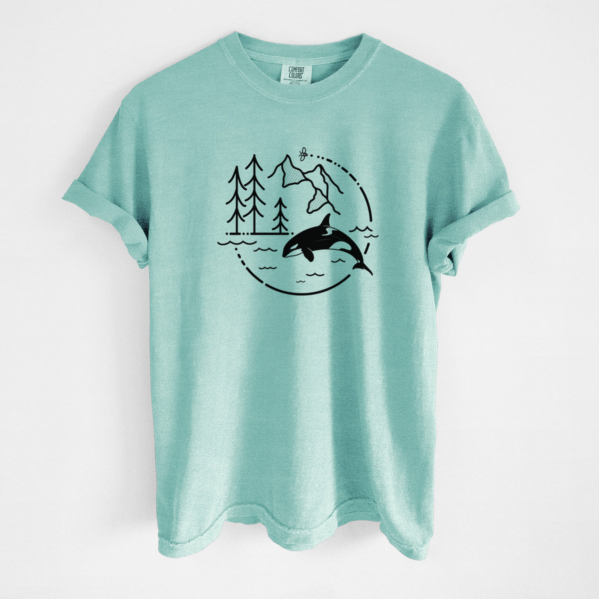 Chalky mint Comfort Colors t-shirt laid flat, printed with a black line art circle connecting pine trees, mountains, a bee and an orca leaping from ocean waves.