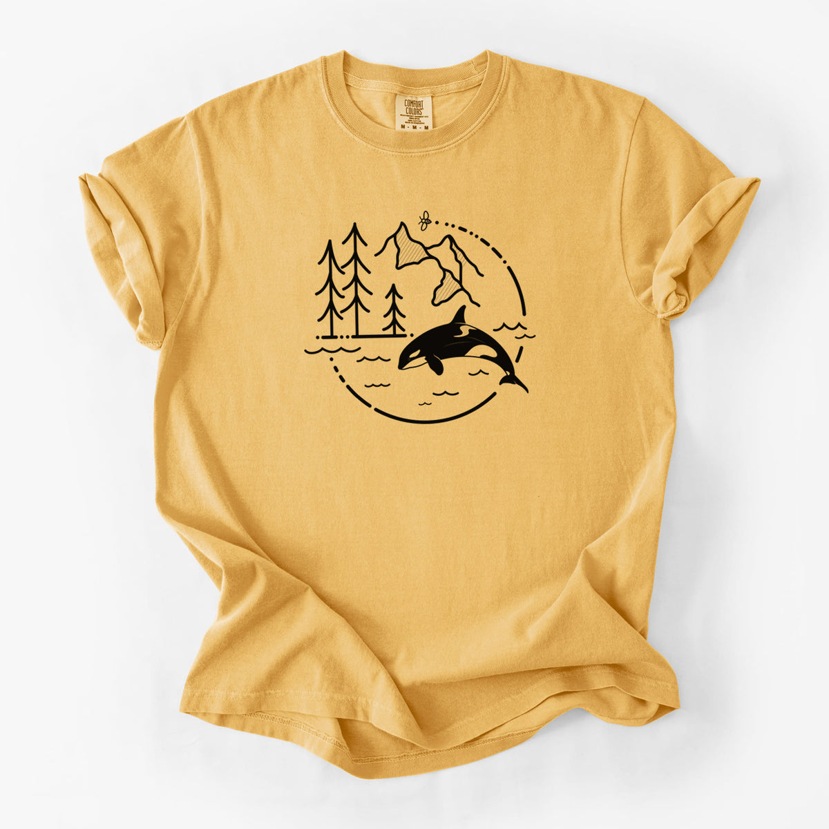 Golden wheat yellow Comfort Colors t-shirt laid flat, printed with a black line art circle connecting pine trees, mountains, a bee and an orca leaping from ocean waves.