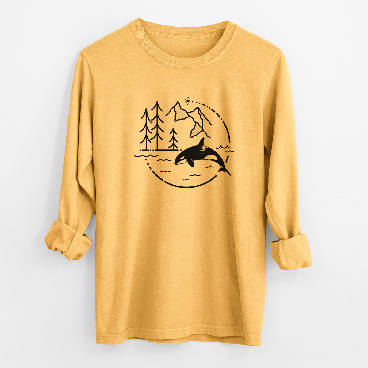 Golden wheat yellow Comfort Colors long sleeve shirt laid flat with the cuffs rolled, printed with a black line art circle connecting pine trees, mountains, a bee and an orca leaping from ocean waves.