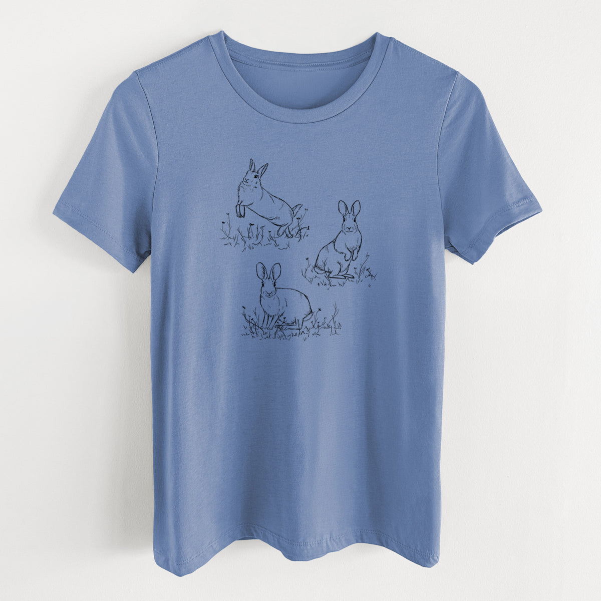 Blue bell women's relaxed fit cotton t-shirt laid flat, printed with a black ink illustration of three cottontail rabbits among grass and flowers.