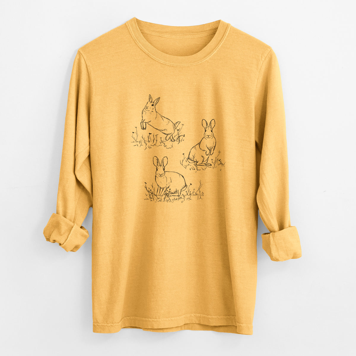 Golden wheat yellow Comfort Colors long sleeve shirt laid flat with the cuffs rolled, printed with a black ink illustration of three cottontail rabbits among grass and flowers.