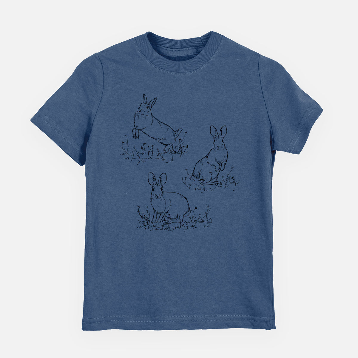Indigo blue youth t-shirt laid flat, printed with a black ink illustration of three cottontail rabbits among grass and flowers.