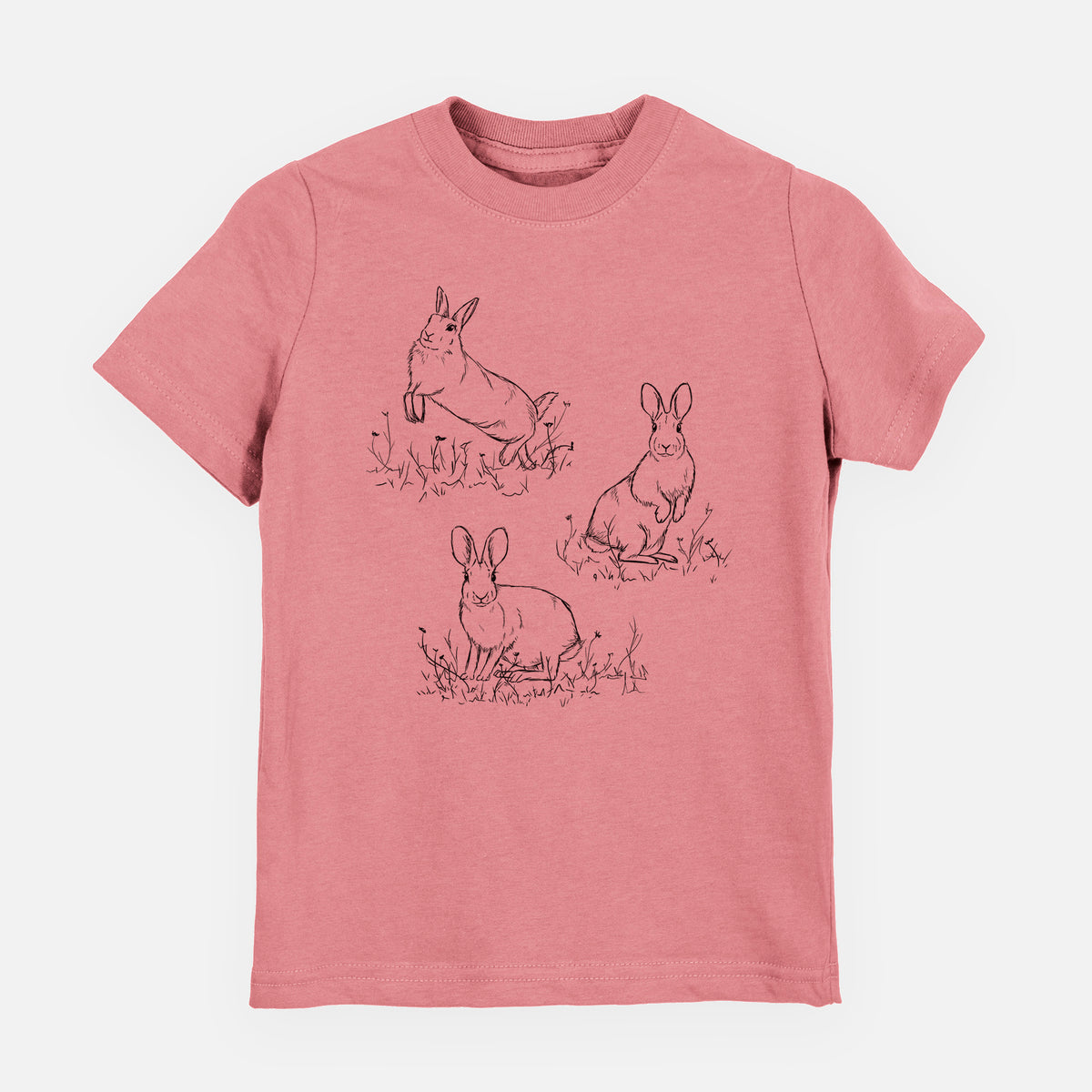 Mauve pink youth t-shirt laid flat, printed with a black ink illustration of three cottontail rabbits among grass and flowers.