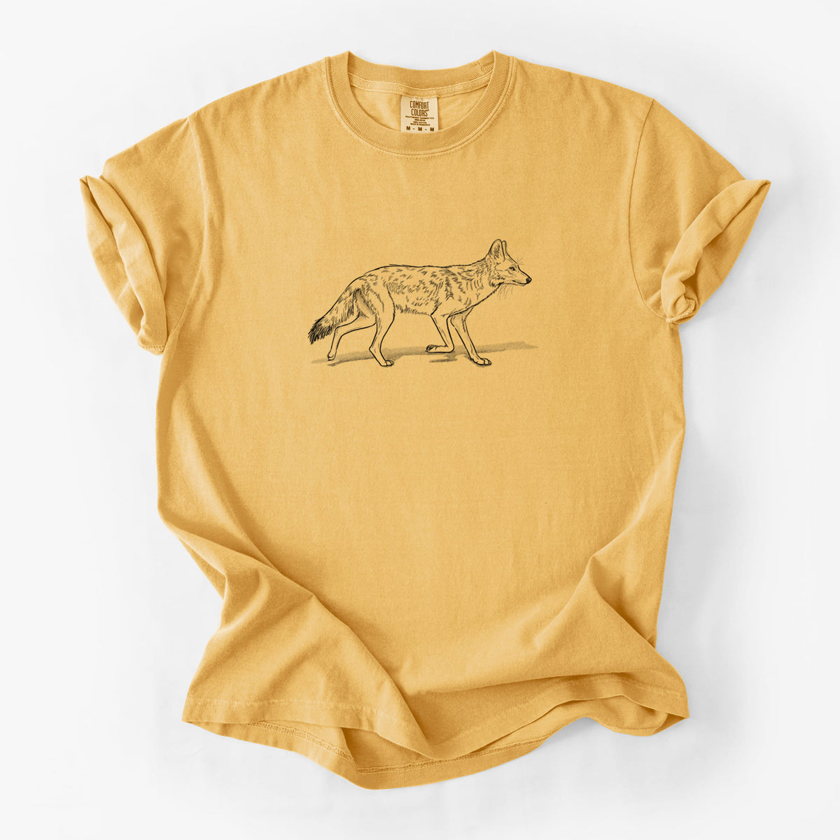 Golden wheat yellow Comfort Colors t-shirt laid flat, printed with a black ink illustration of a coyote trotting.
