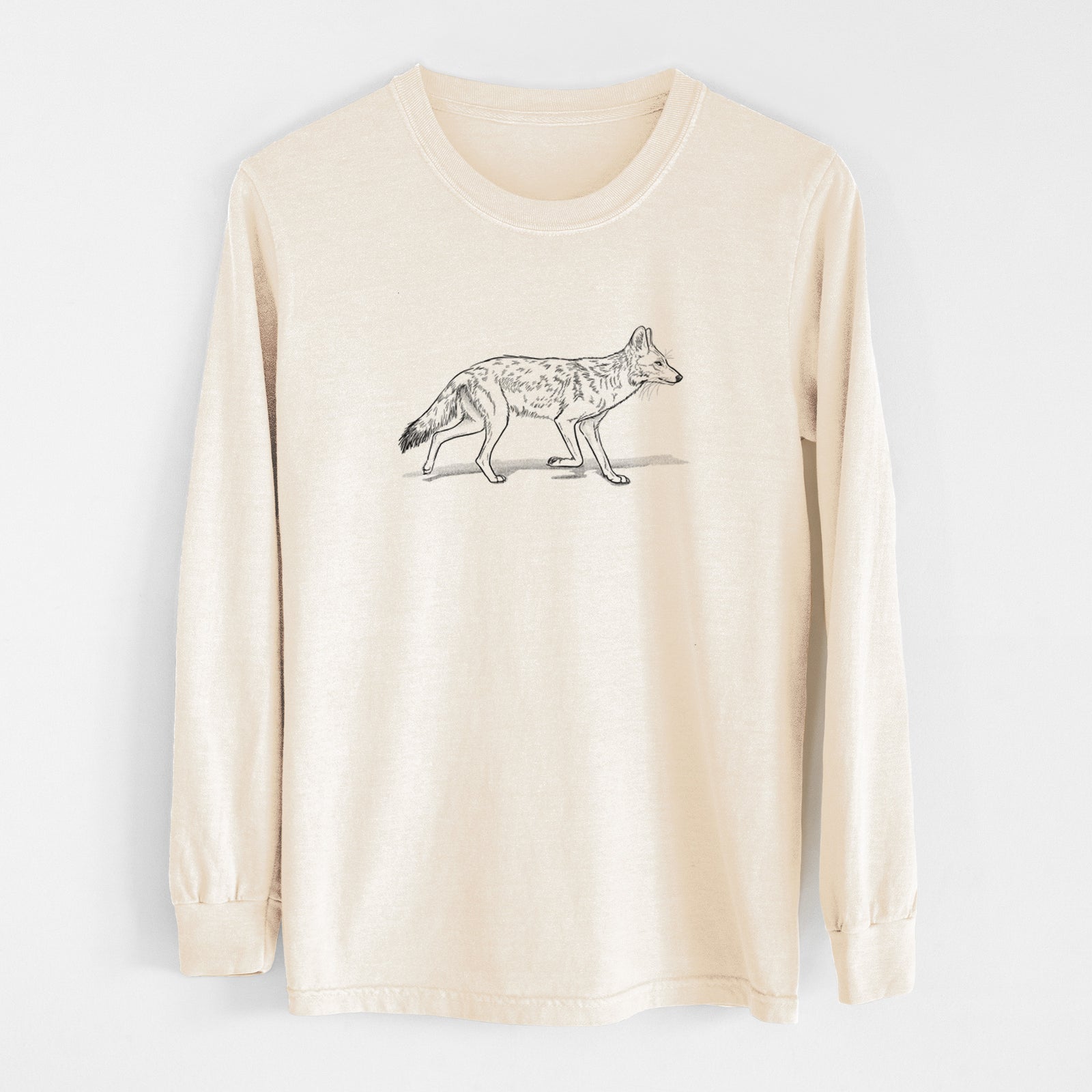 Ivory Comfort Colors long sleeve shirt laid flat, printed with a black ink illustration of a coyote trotting.