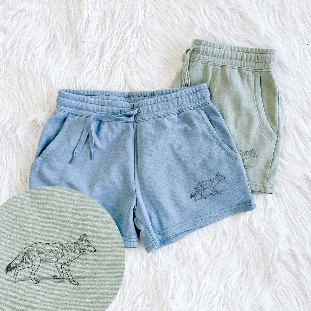 Two pairs of Cali Wave shorts in different colors printed with a black ink illustration of a coyote trotting, with a close-up of the print.