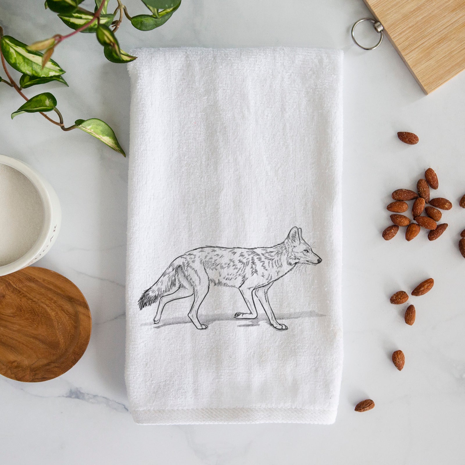 White hand towel printed with a black ink illustration of a coyote trotting.
