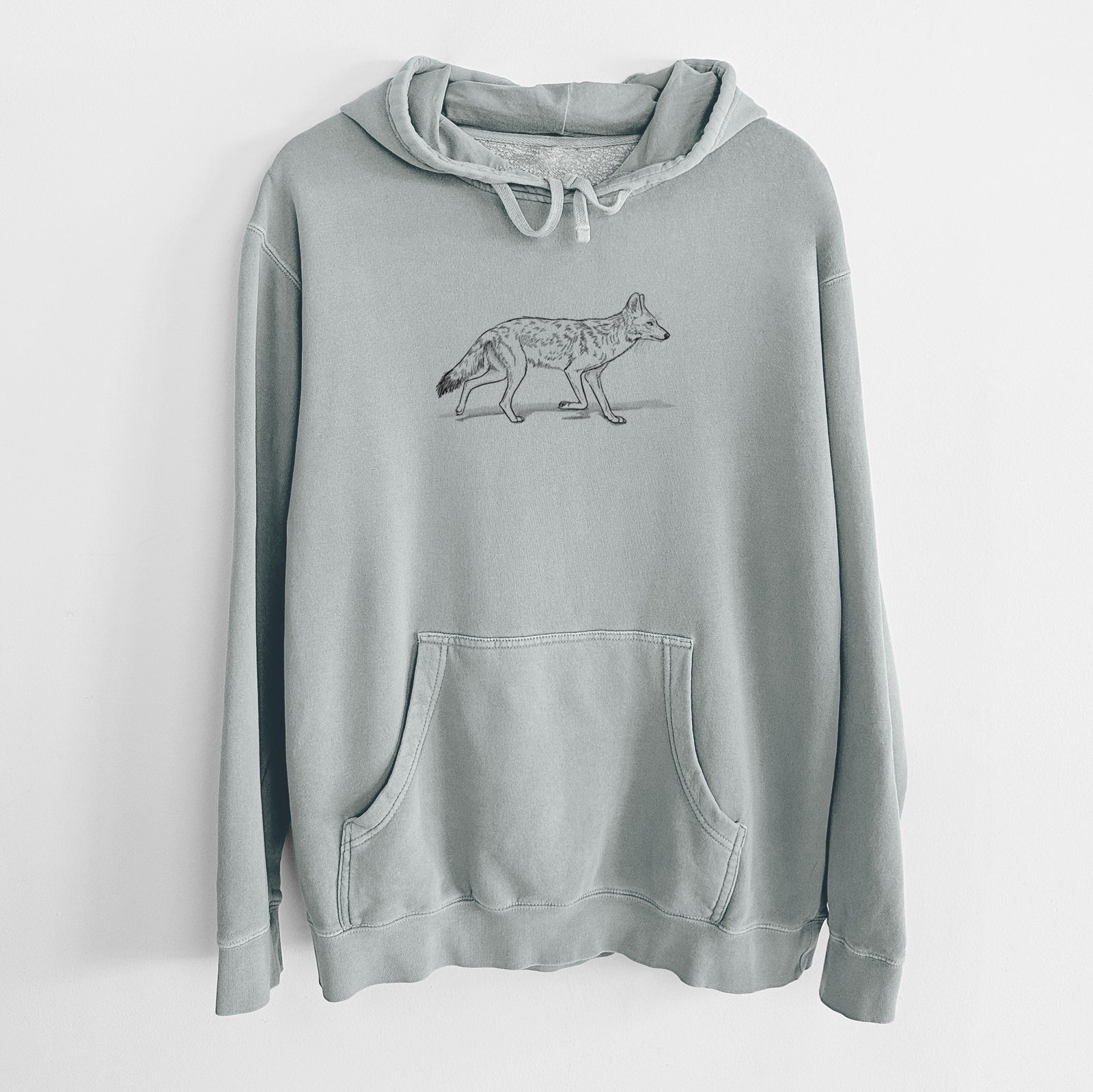 Sage green pigment dyed hoodie laid flat, printed with a black ink illustration of a coyote trotting.