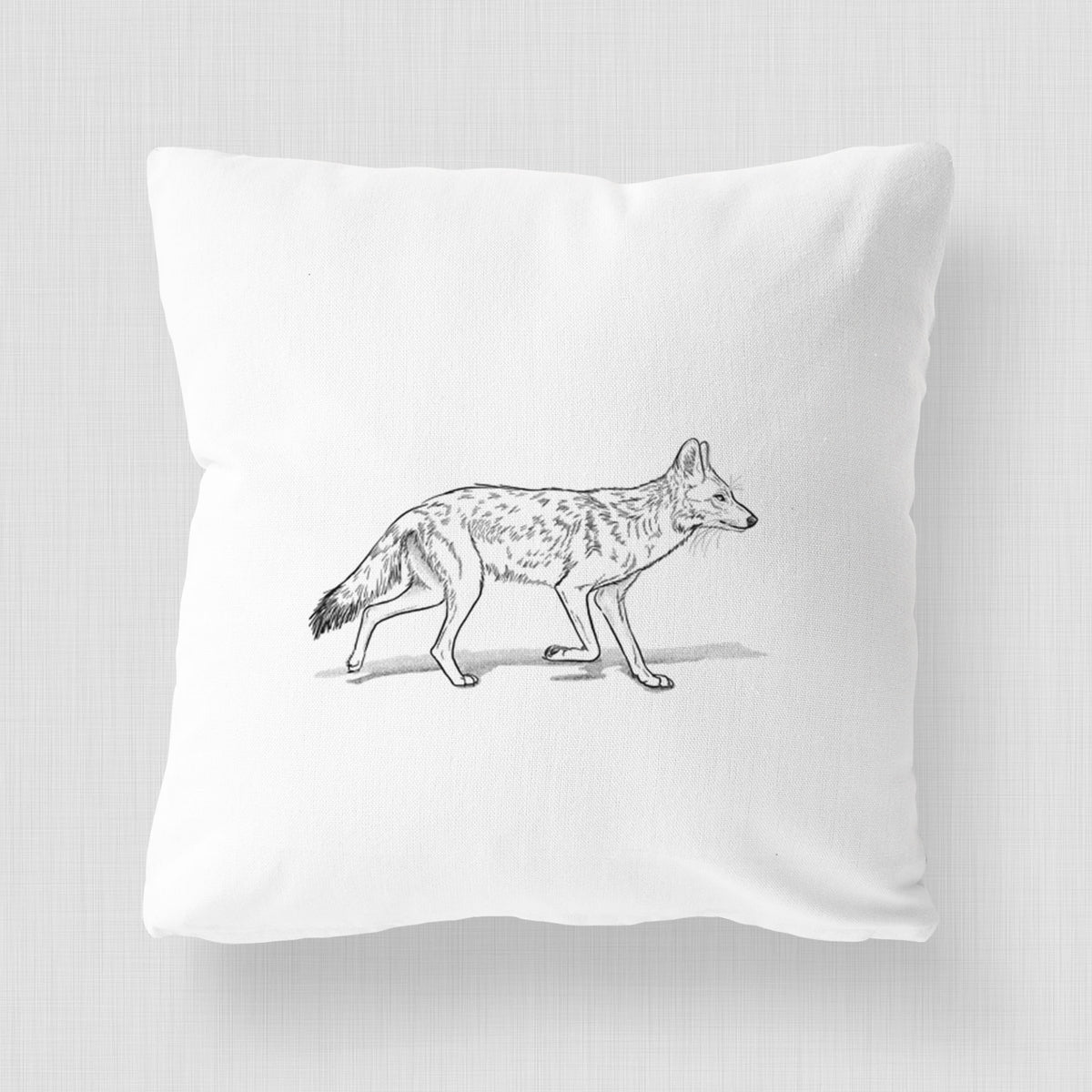 White pillow cover printed with a black ink illustration of a coyote trotting.
